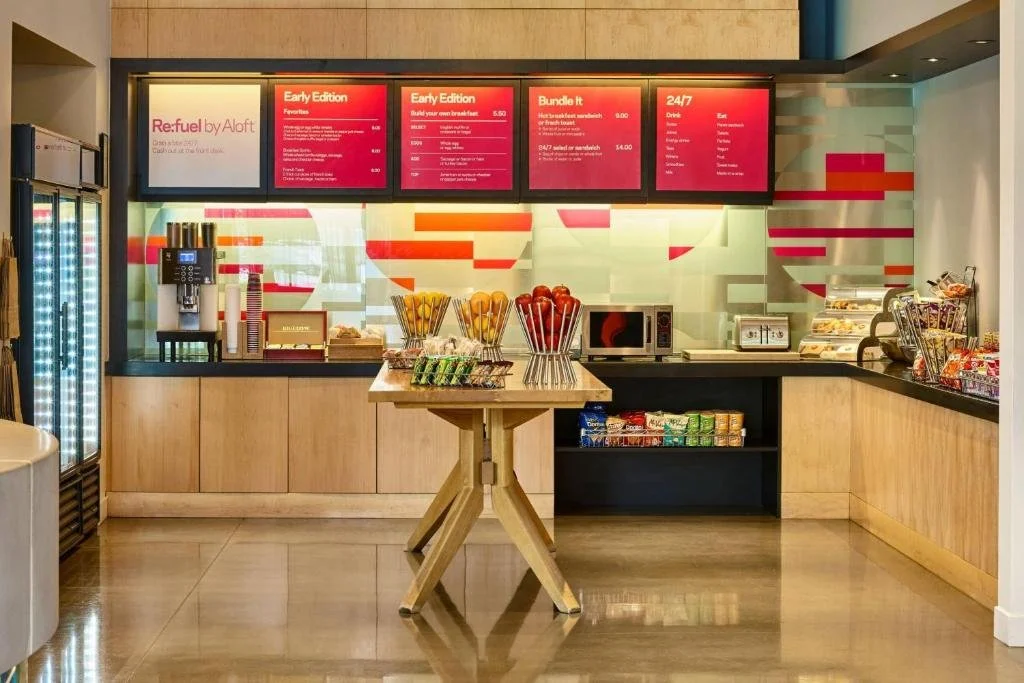 Coffee and snack bar with digital menu boards, a fruit display, and snack shelves.