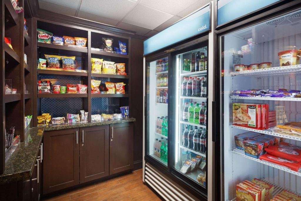 A small snack and beverage display area in a store with snacks on open shelves and drinks in refrigerated coolers.