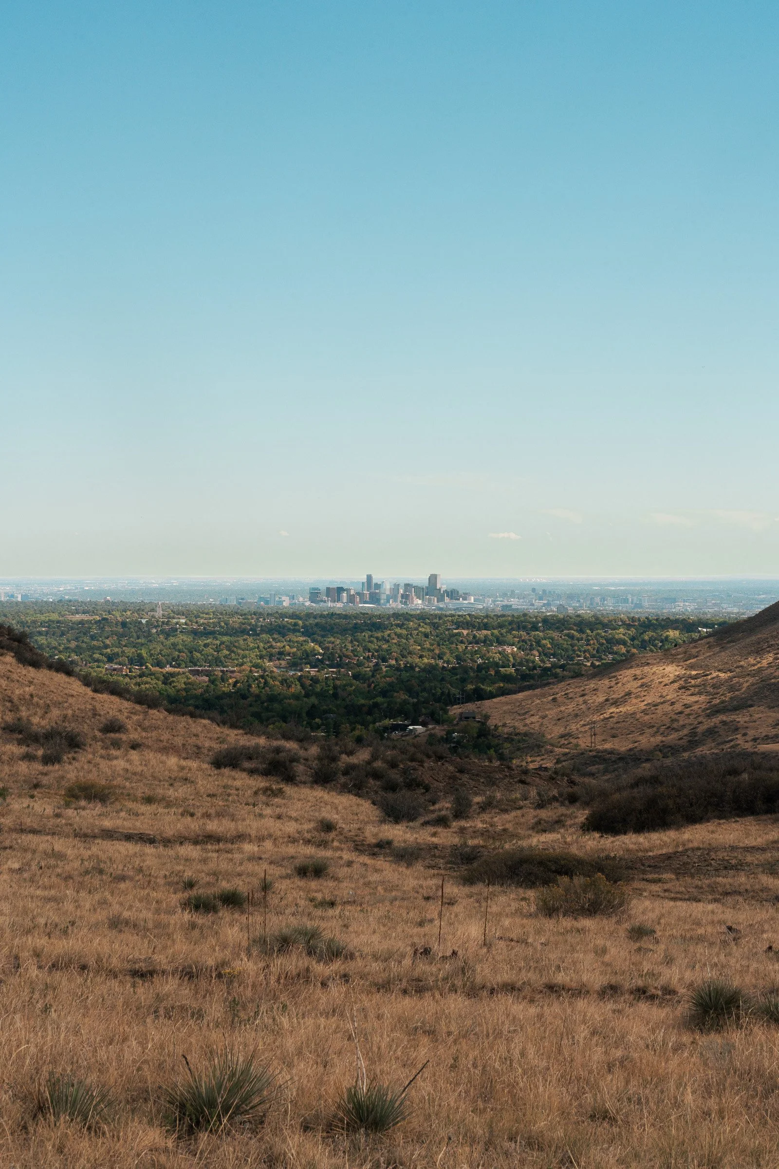 Downtown Denver visible in the distance between two hills from South Table Mountain.