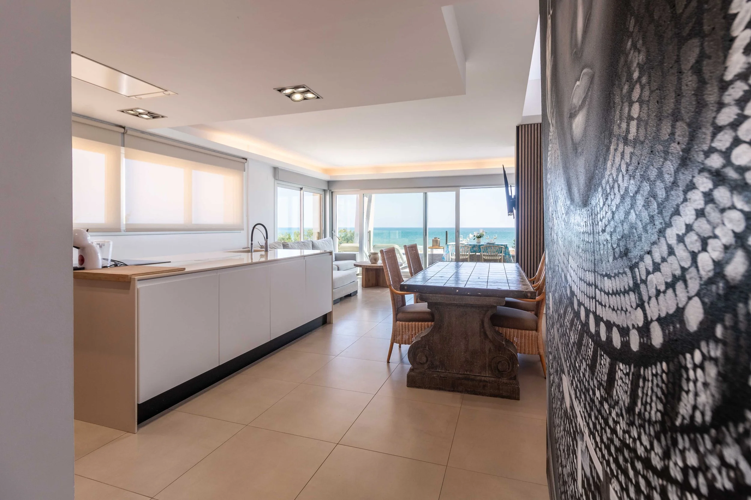 Interiores de una sala de comedor con vista al mar, ventana grande y decoración moderna.