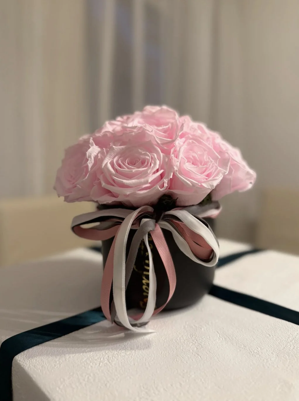 Rosa roser i elegant sort blomsterboks med dekorative bånd fra Everlasting.no