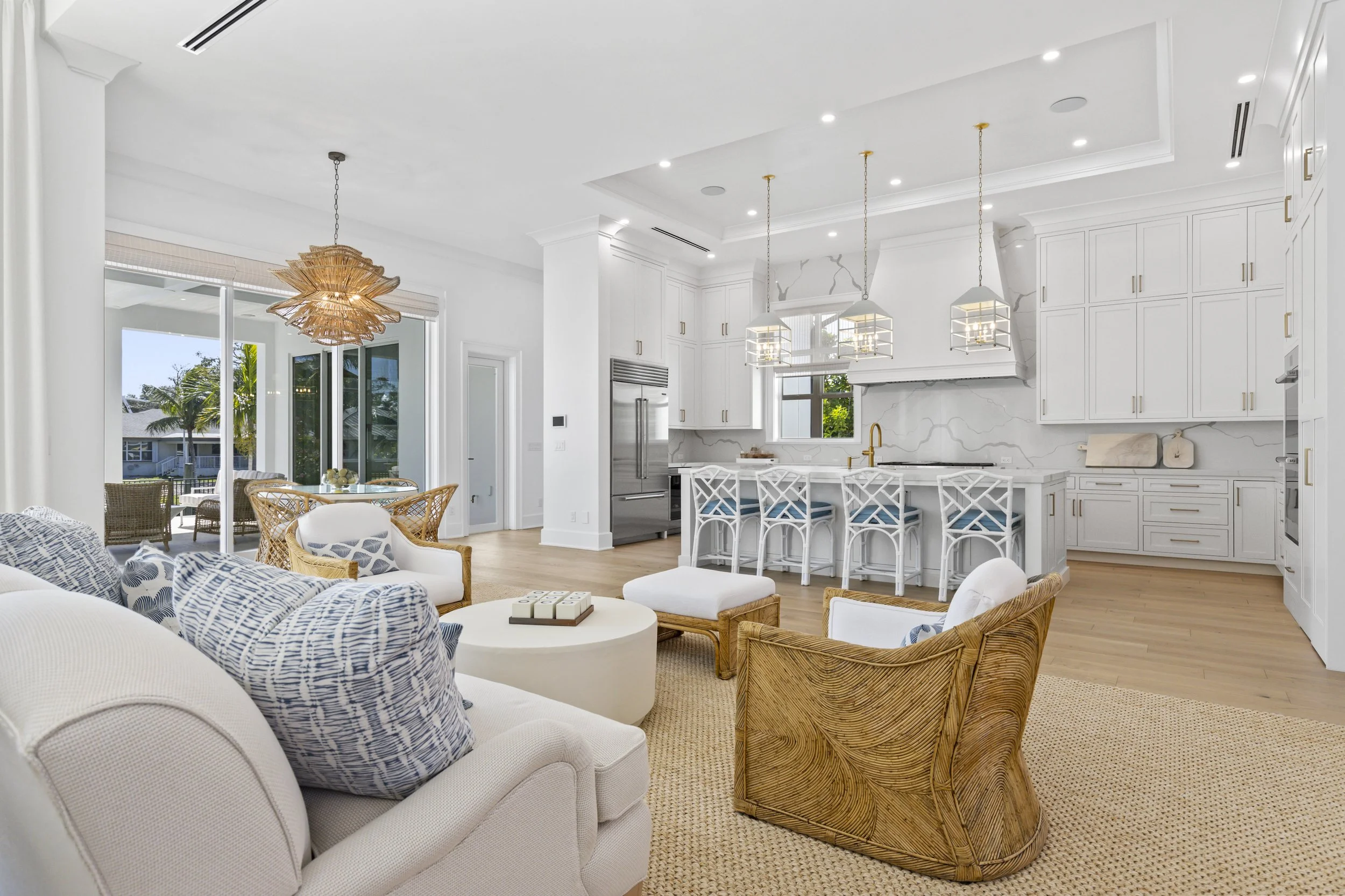 Bright, modern kitchen and living room with white cabinetry, marble backsplash, and pendant lighting, with outdoor patio visible through glass sliding doors.
Professional real estate photo taken by Lee at PH MEDIA of a home in vero beach florida