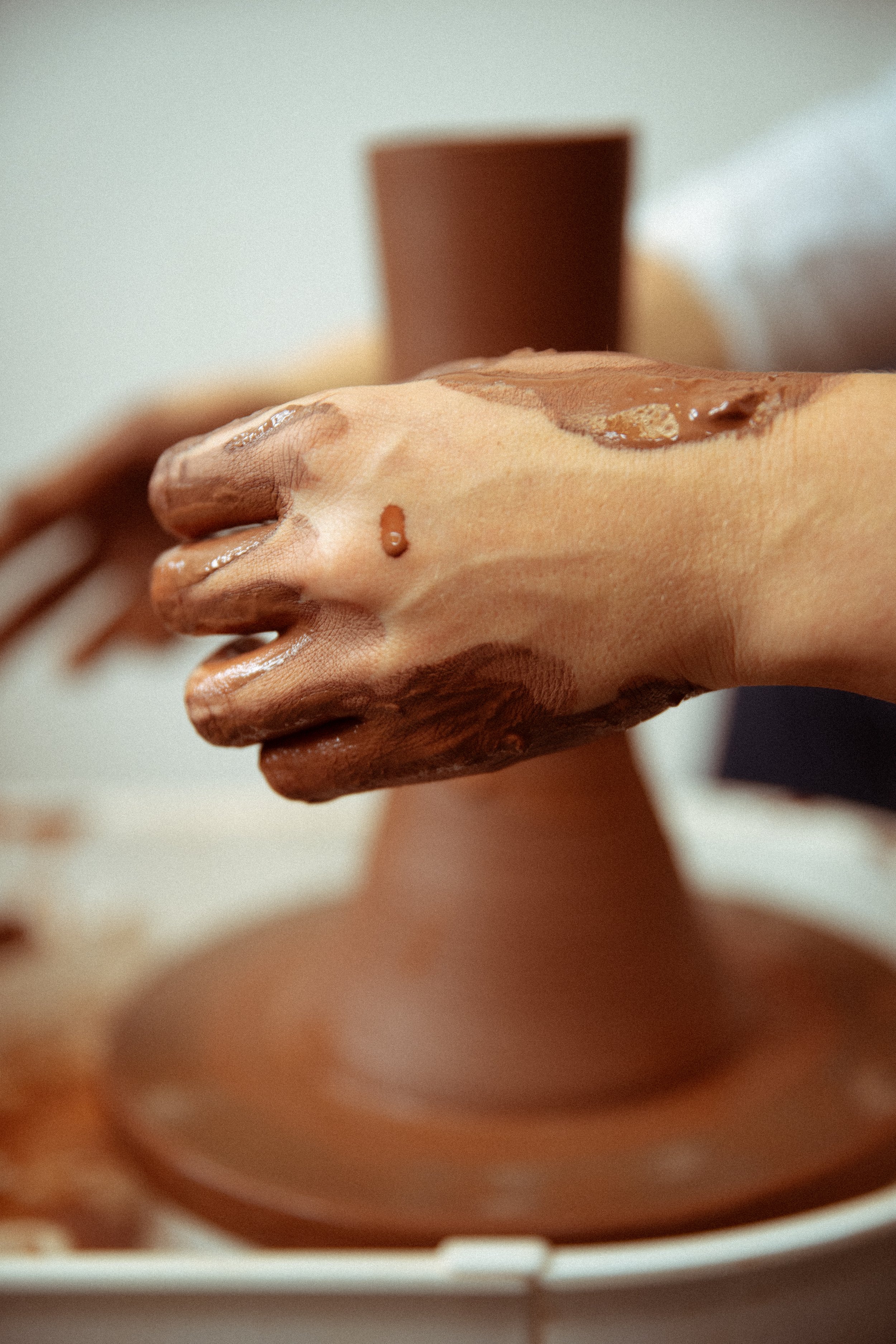 A hand with chocolate ice cream on fingers and palm, with a chocolate cone in the background.