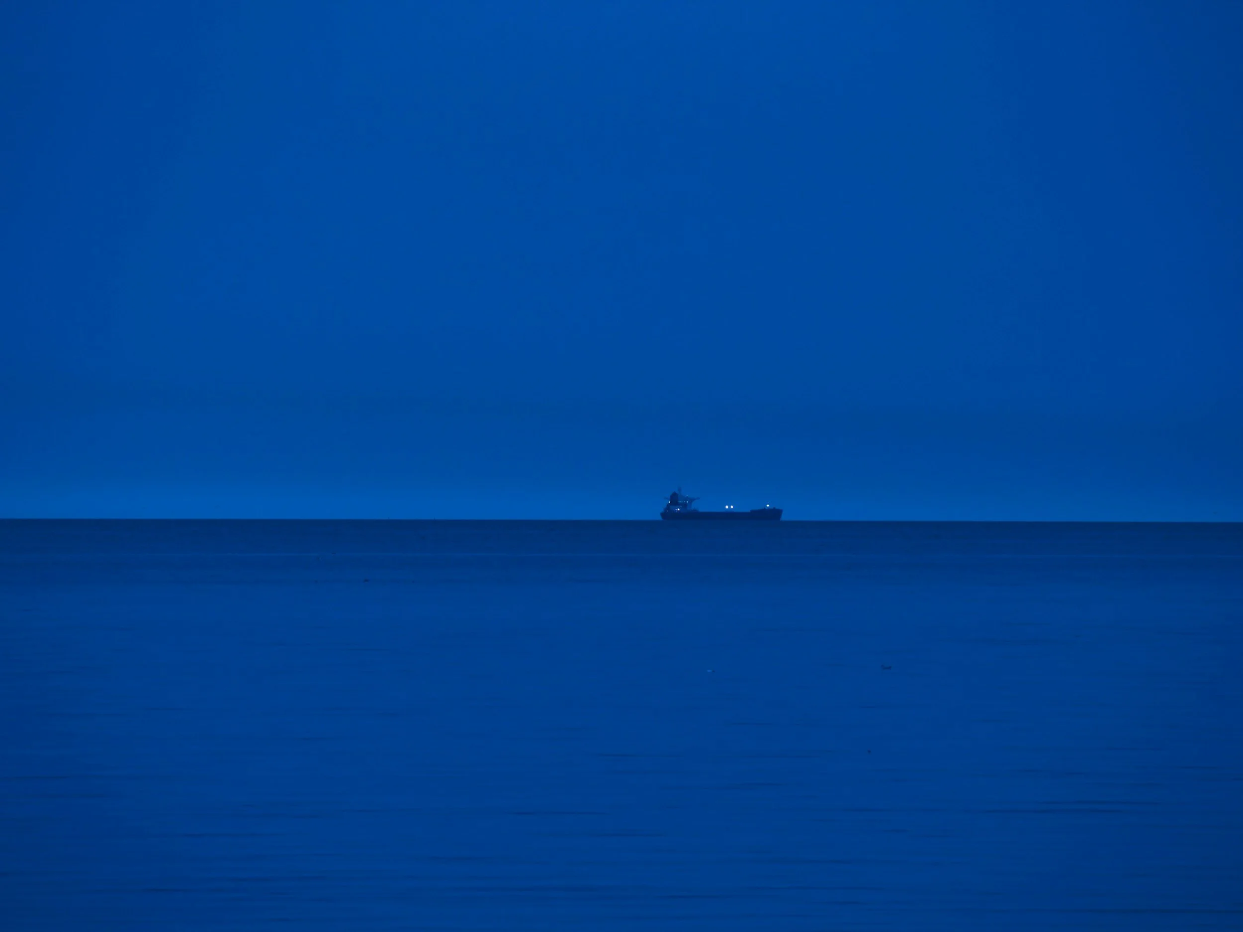 A ship sailing on the ocean under a clear, blue sky.