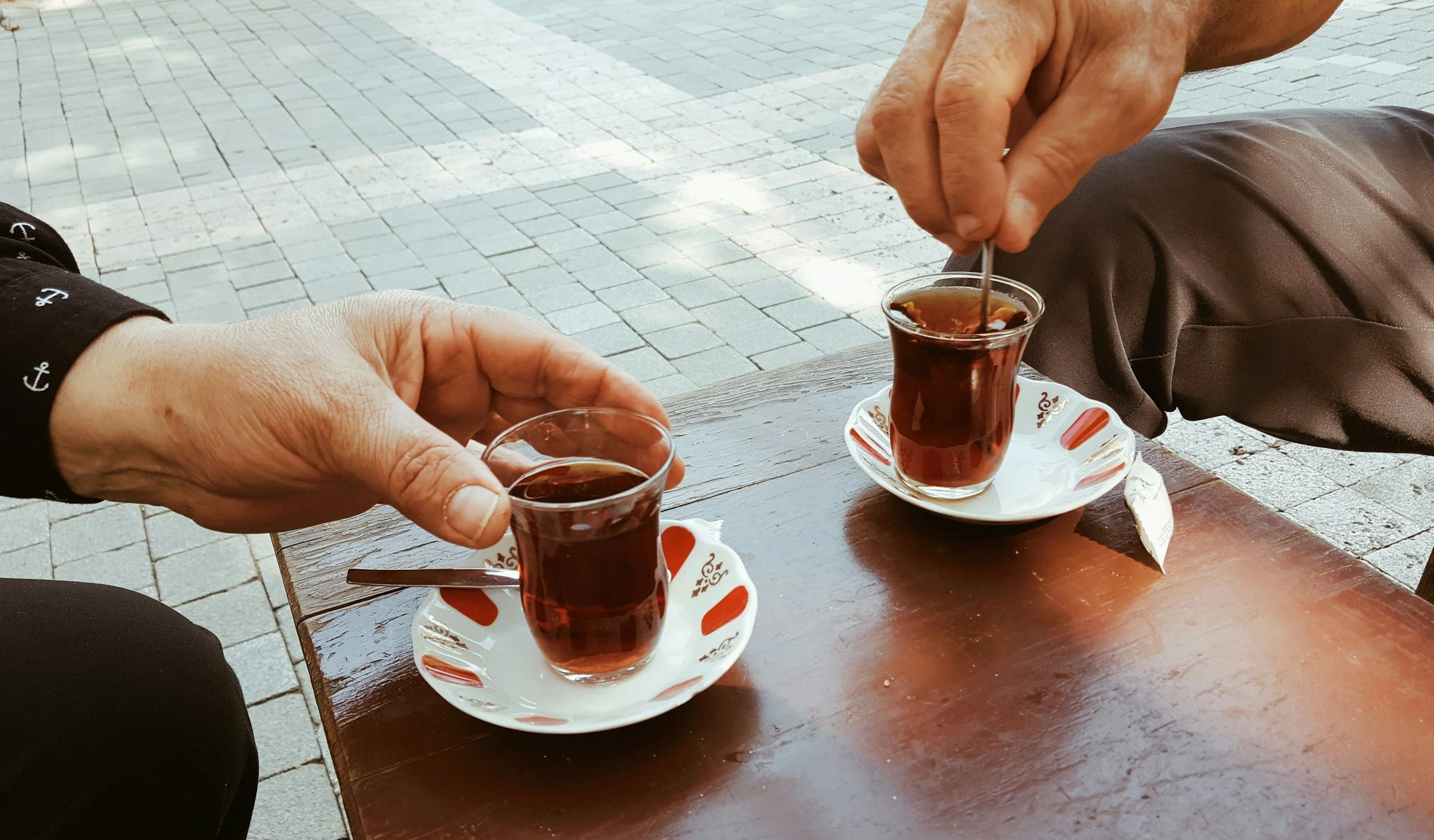 Two people sharing glasses of Turkish tea at a table