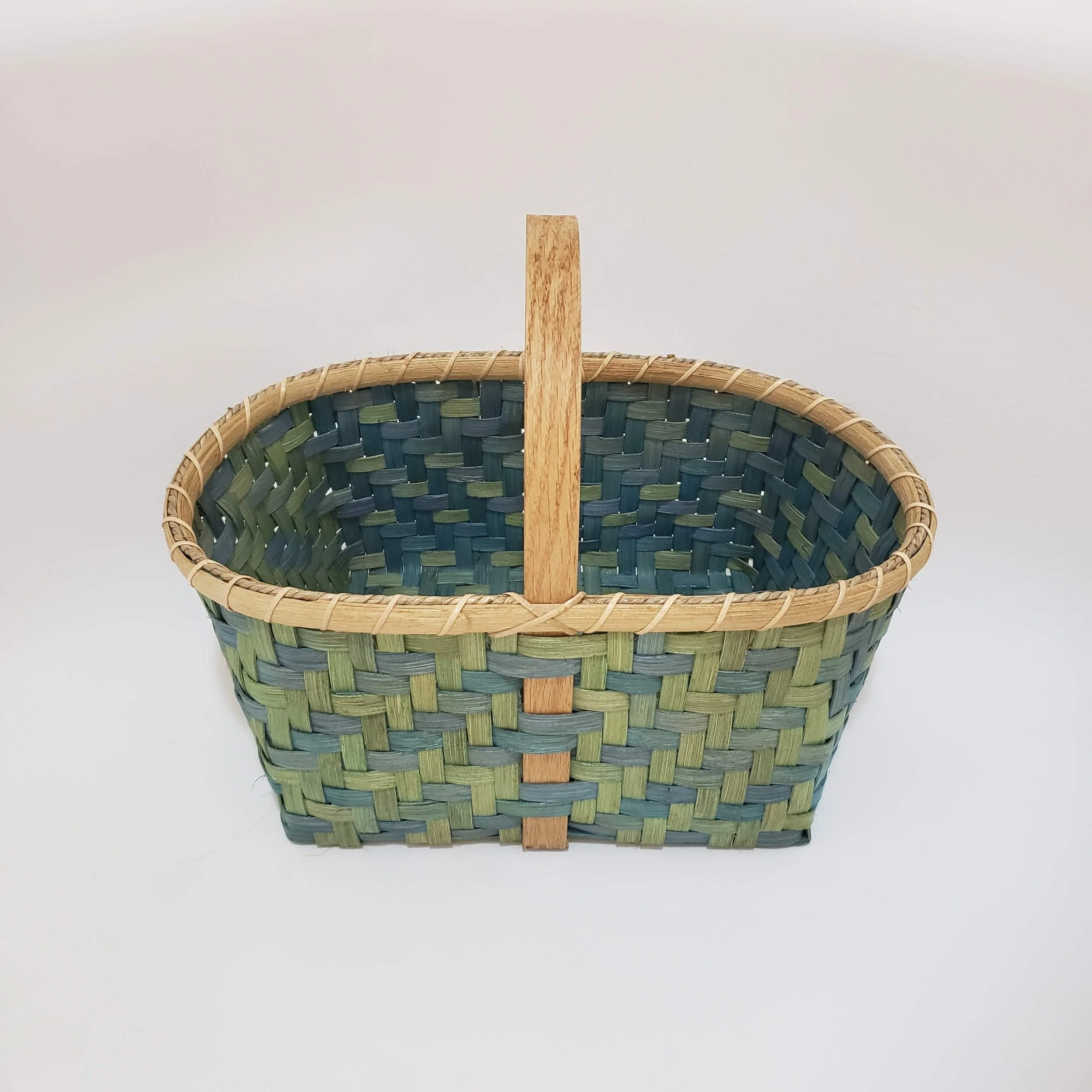 A woven basket with a wooden handle against a white background.