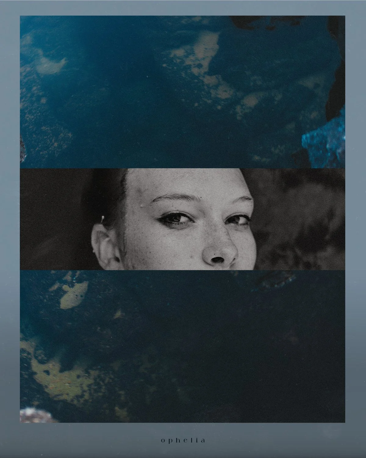 Close-up of a woman's face with dark eyes and freckles, partially submerged in water with a reflection of the sky.
