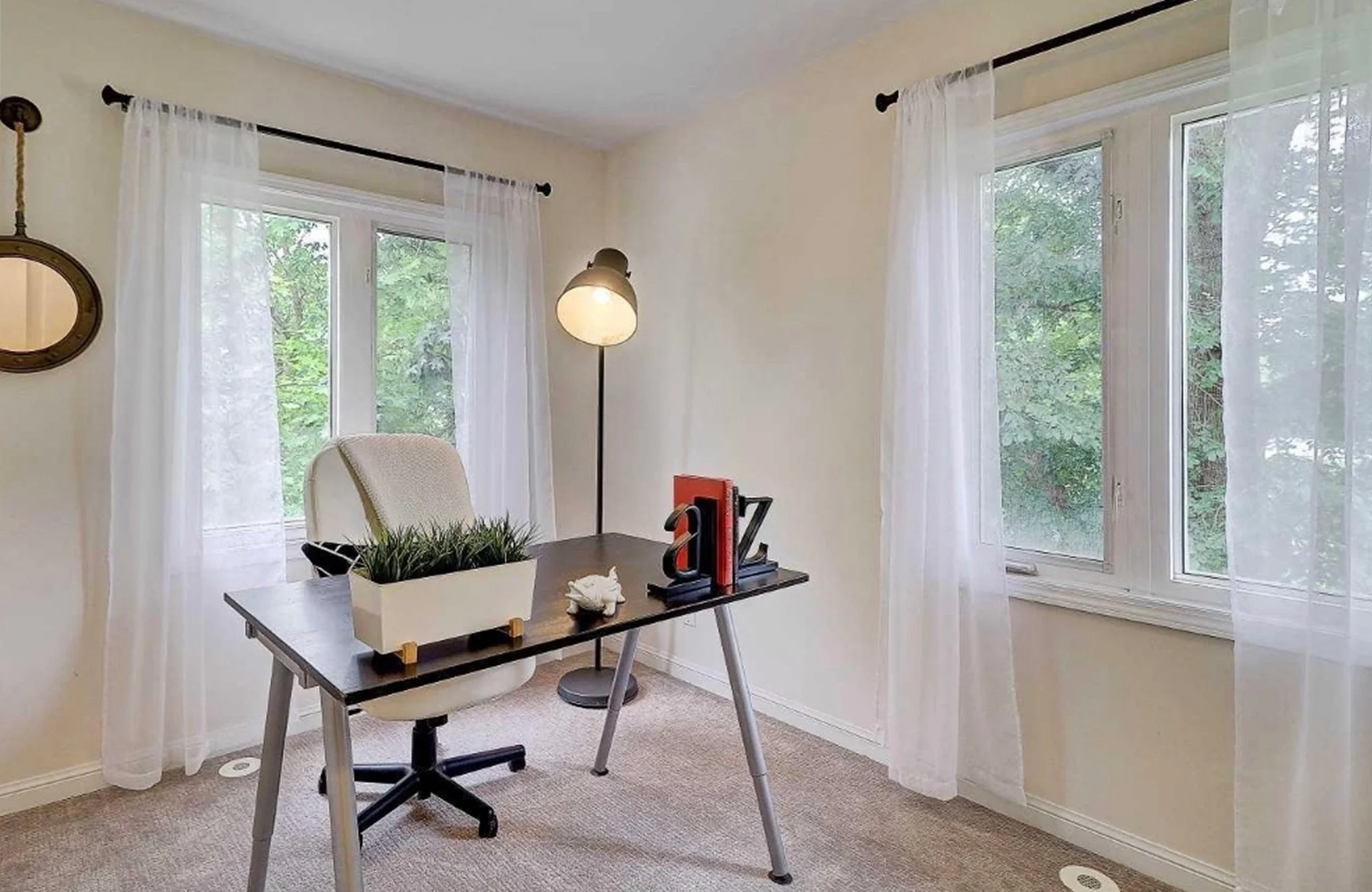Before photo of THE OASIS office, staged with a simple desk, office chair, and floor lamp, ahead of the full renovation