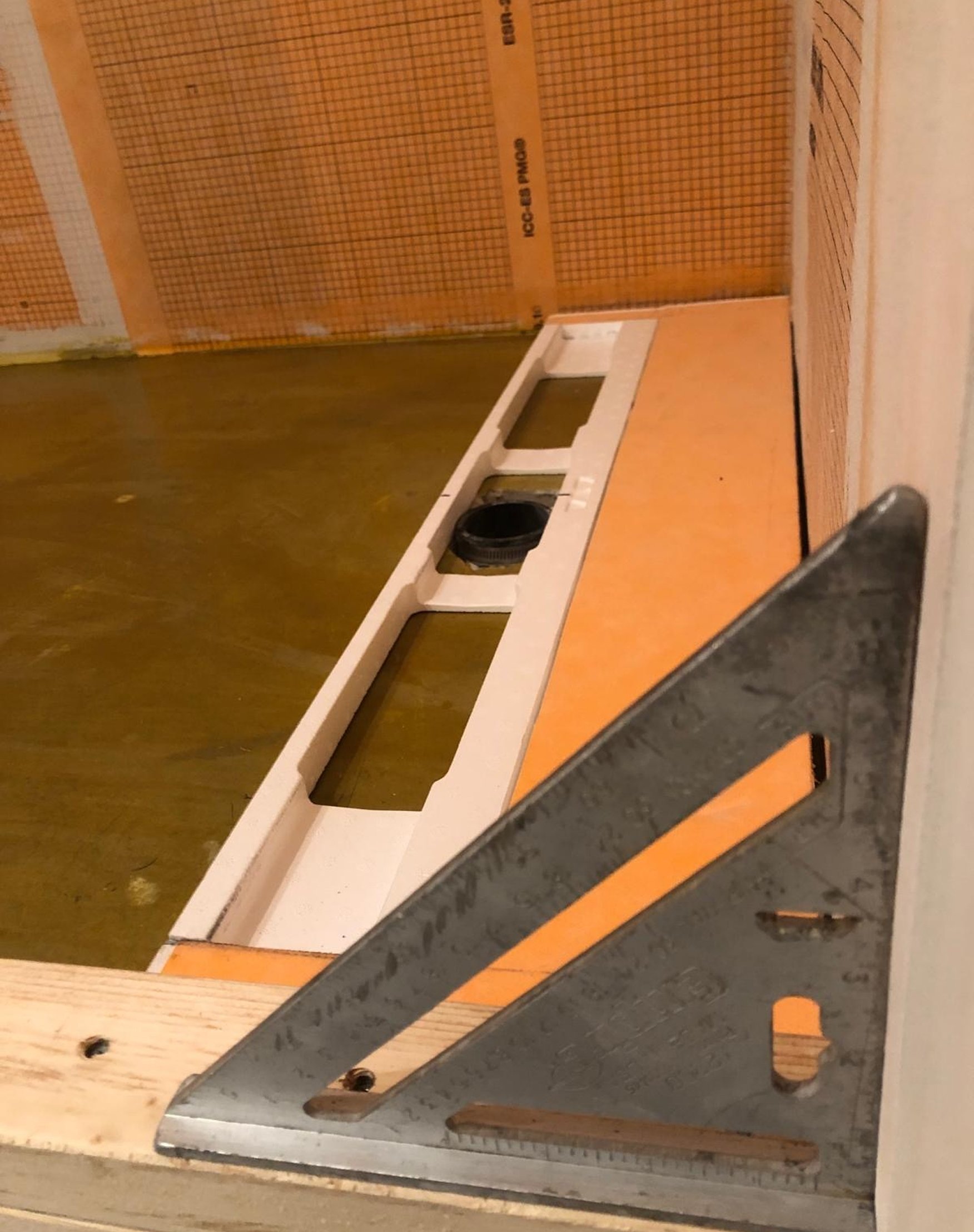 Confirming a perfect level before moving on to tile — the self-leveling compound cured exactly flat around the drain.