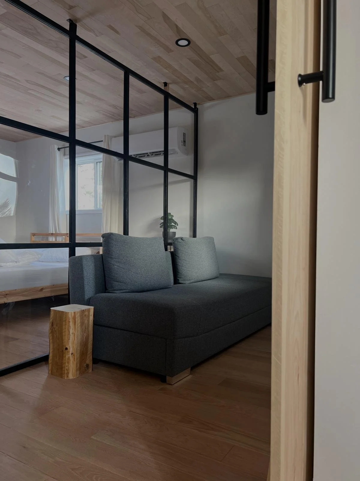 Black steel-framed glass partition dividing a bedroom and living area in a Toronto interior renovation