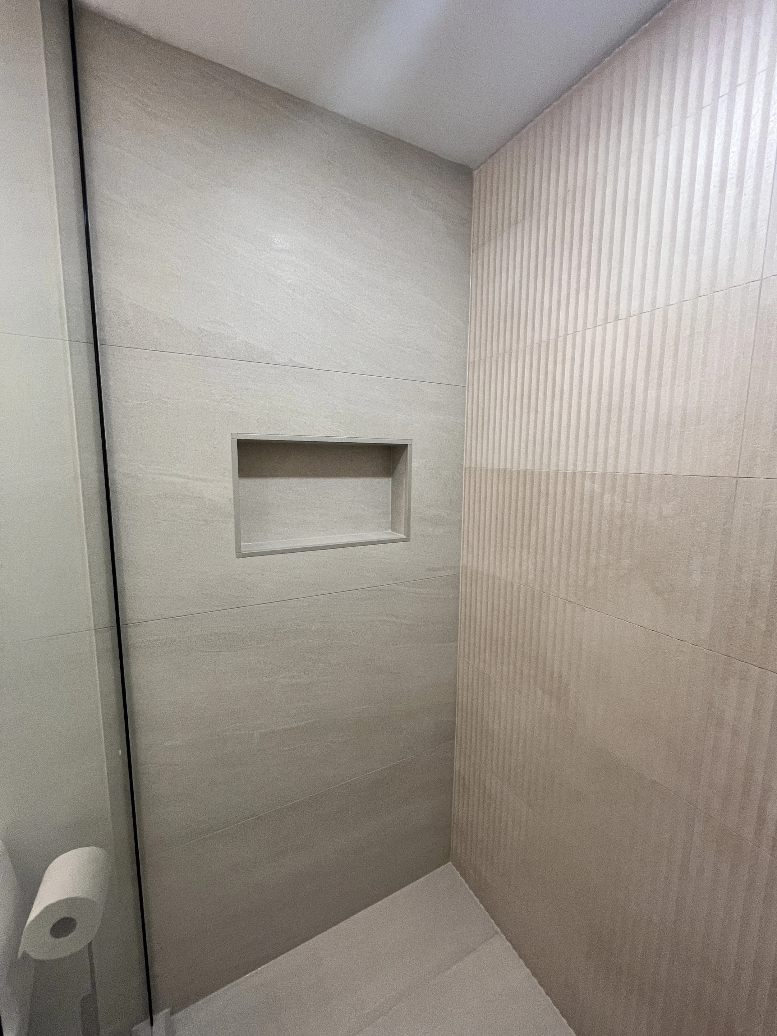 A closer look at the shower's tile work — the mix of large-format stone-look tile and fluted accent tile adds texture without overcomplicating the small space.