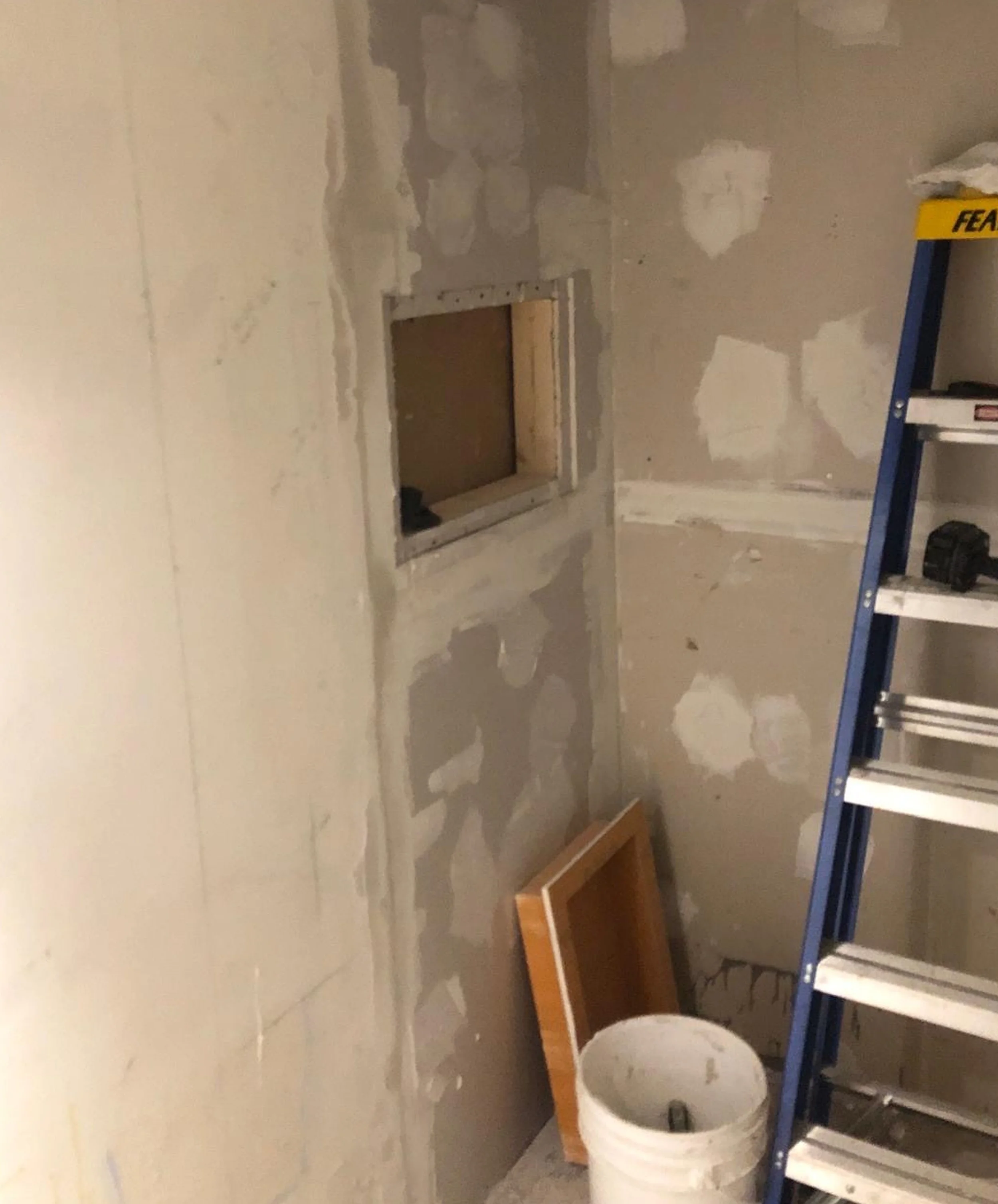 Mid-construction — drywall mudded and the shower niche framed in, one of the steps before tile goes up.