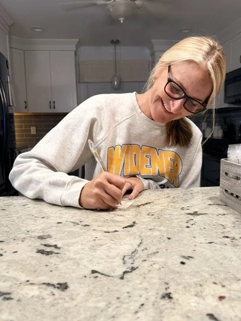 Sara writing a handwritten thank-you card for a customer order