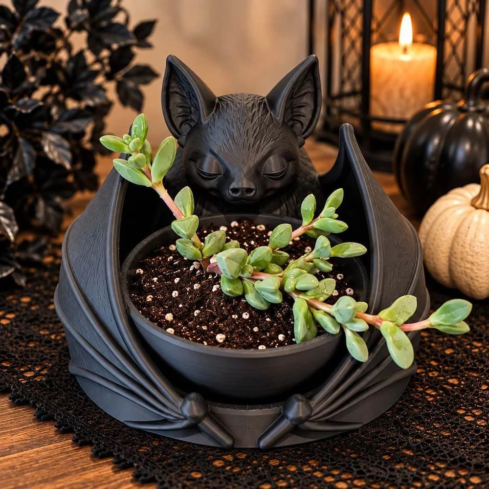 Sitting Bat Planter in matte black holding a succulent, styled with candles and pumpkins
