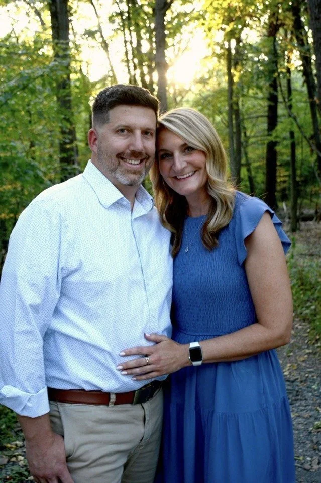 Joe and Sara standing together in a sunlit wood