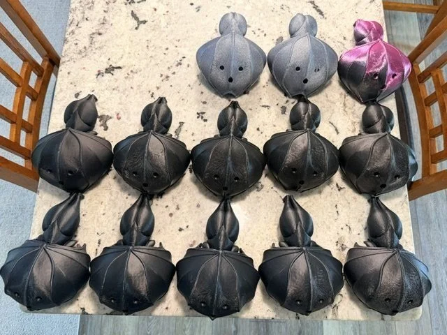 Sixteen hanging bat planters laid out on a counter for finishing
