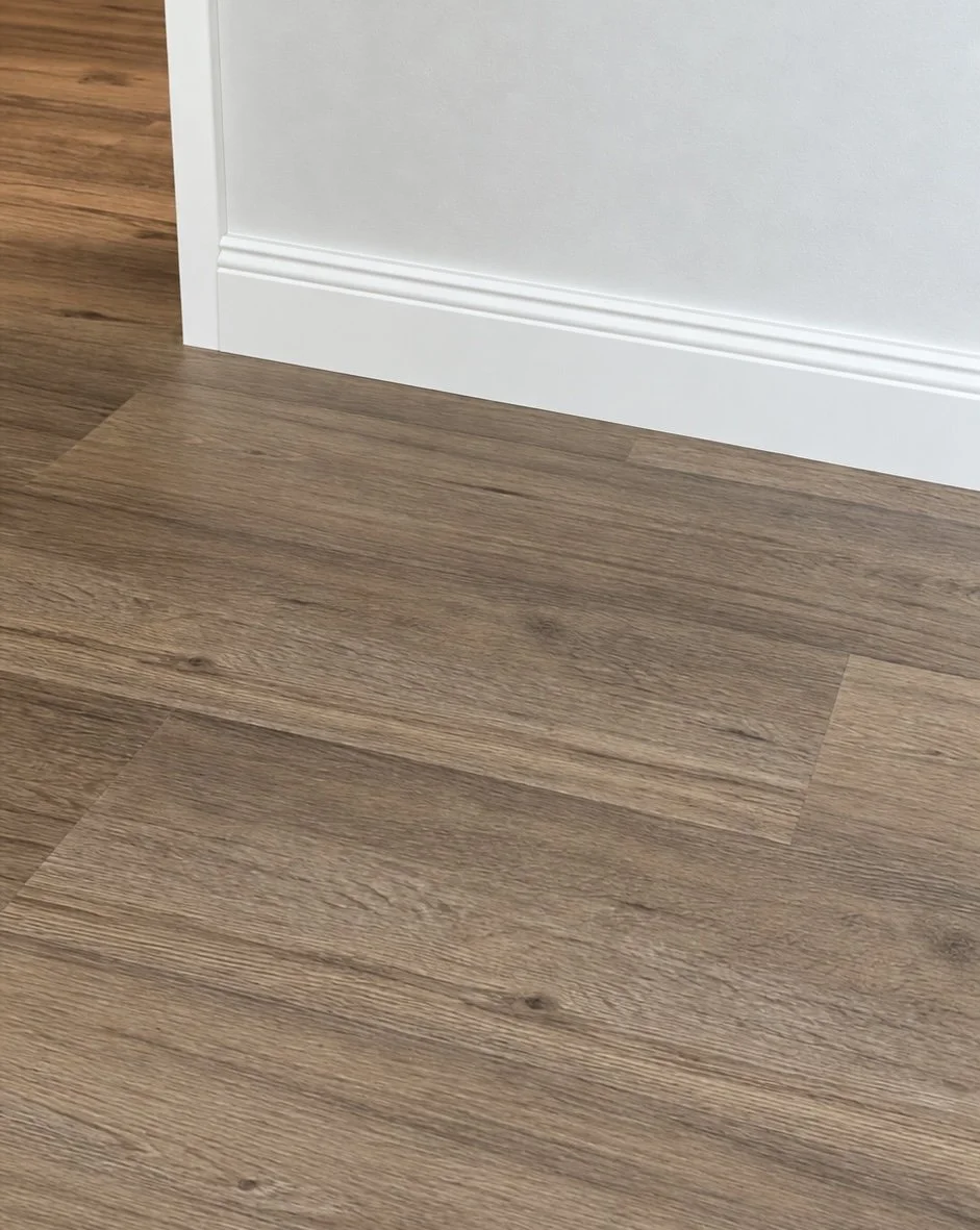 Boden und Sockelleiste im Innenraum, boden aus Holzlaminat und weiße Wand mit Zierleiste