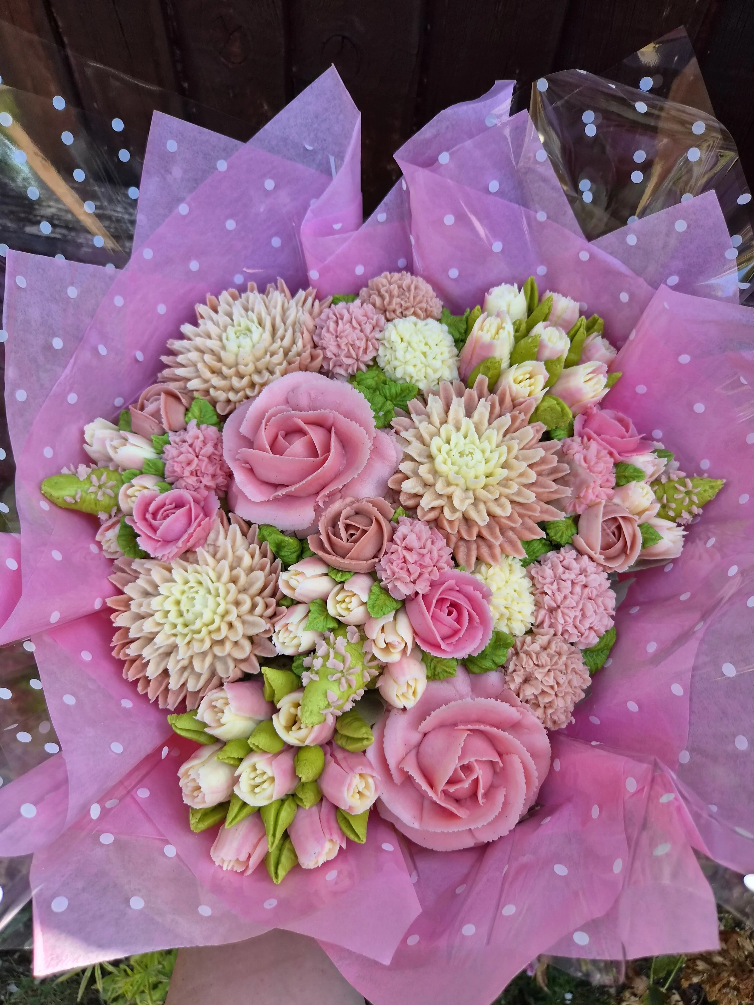 Cupcake Bouquet of pink, cream, and white flowers wrapped in pink tissue paper with polka dots. Made with Vanilla Bean Cupcakes with Vanilla Buttercream