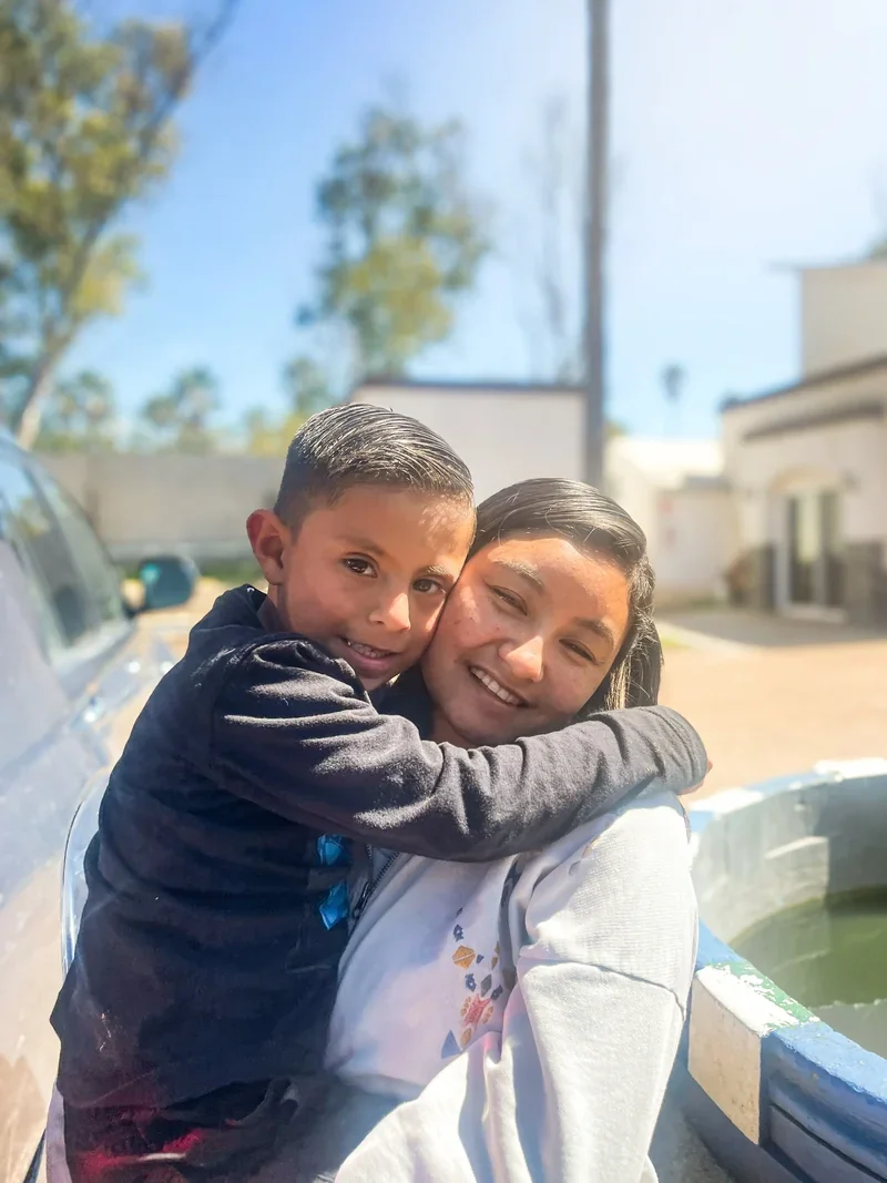 A Mexican boy with his arms around a Mexican woman who is holding him at St. Innocent Orphanage
