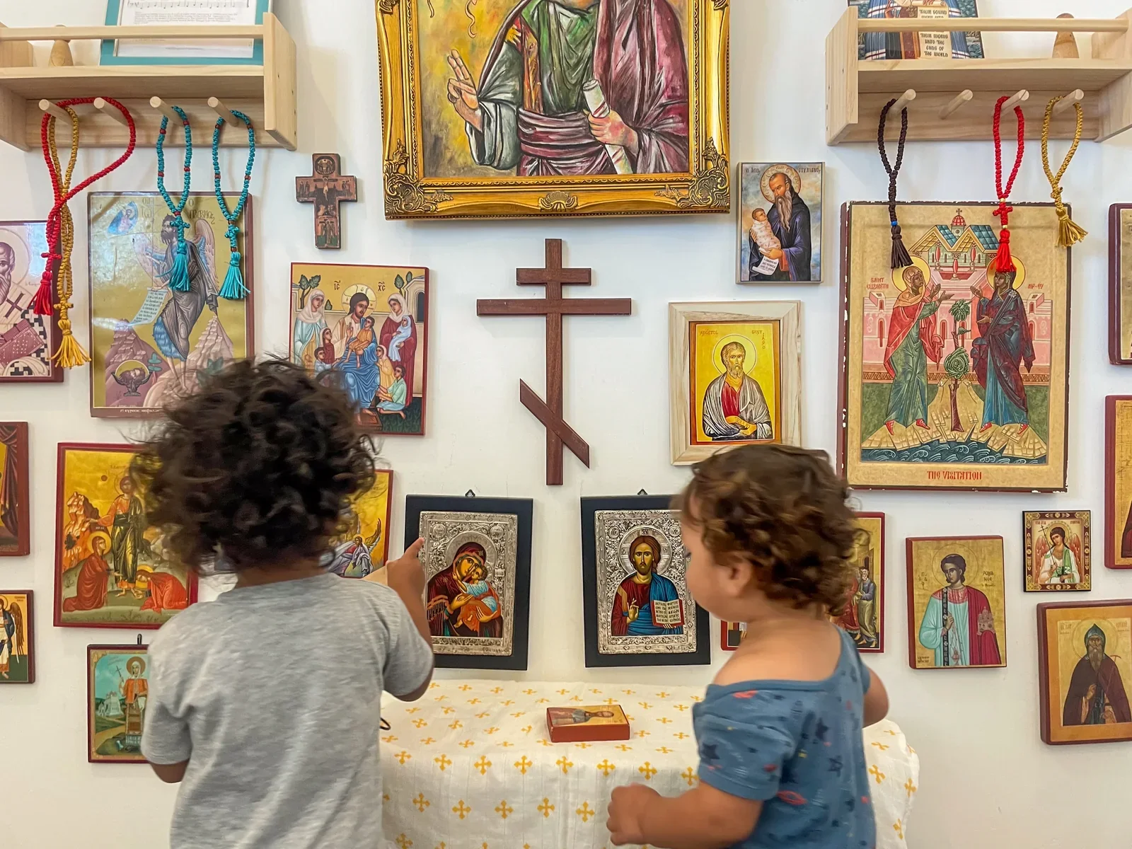Two young Mexican children in front of a wall of Orthodox icons and cross