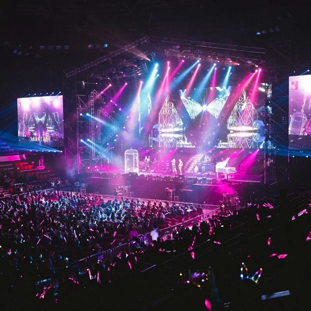 Concert stage with pink and blue lights and a crowd in front
