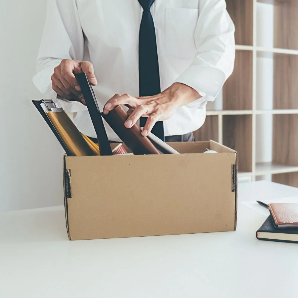 Employee in a shirt and tie packing belongings into a cardboard box