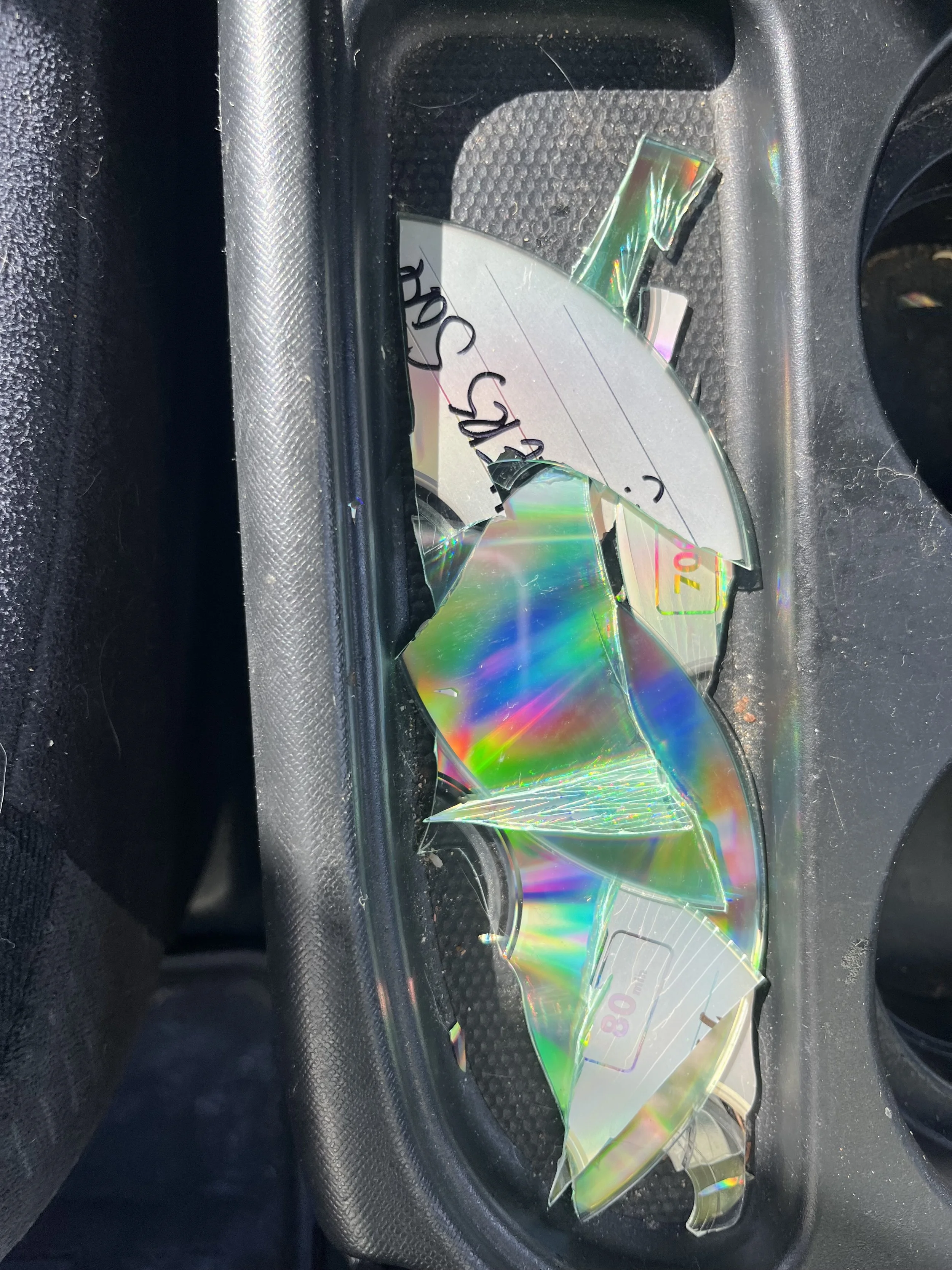 Broken CD/DVD with rainbow reflections on a black textured surface