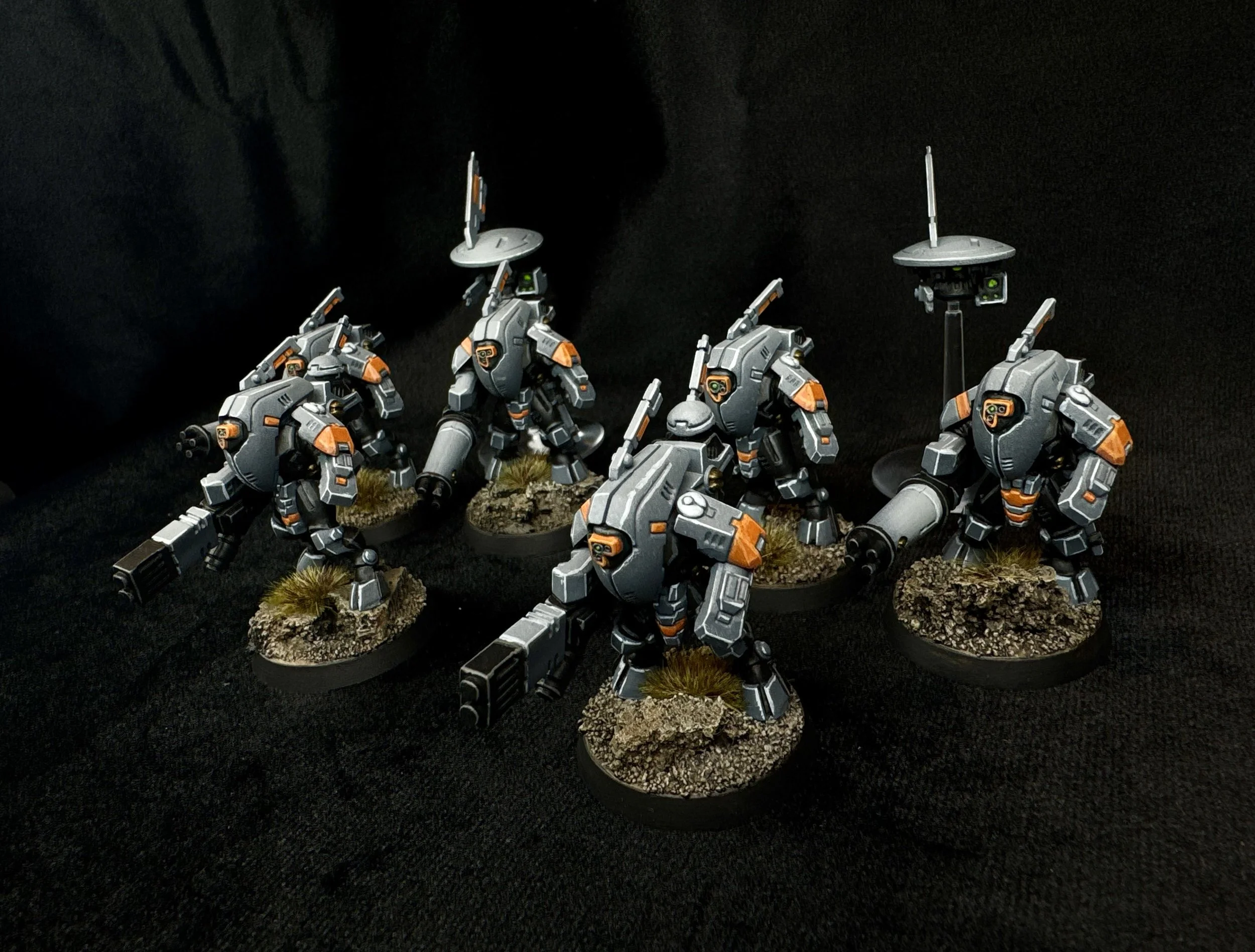 A group of five detailed miniature science fiction robots or mechs with weapons, displayed on textured bases with grass and rocks.