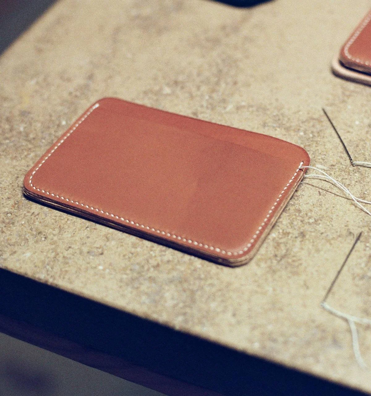 A closed tan leather wallet on a speckled beige countertop.