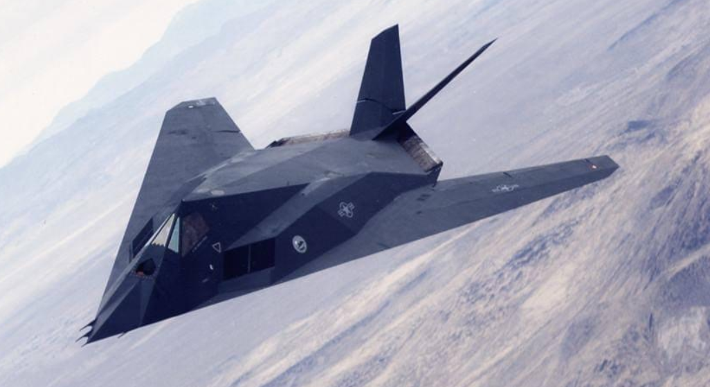 A military fighter jet flying over a snowy landscape.