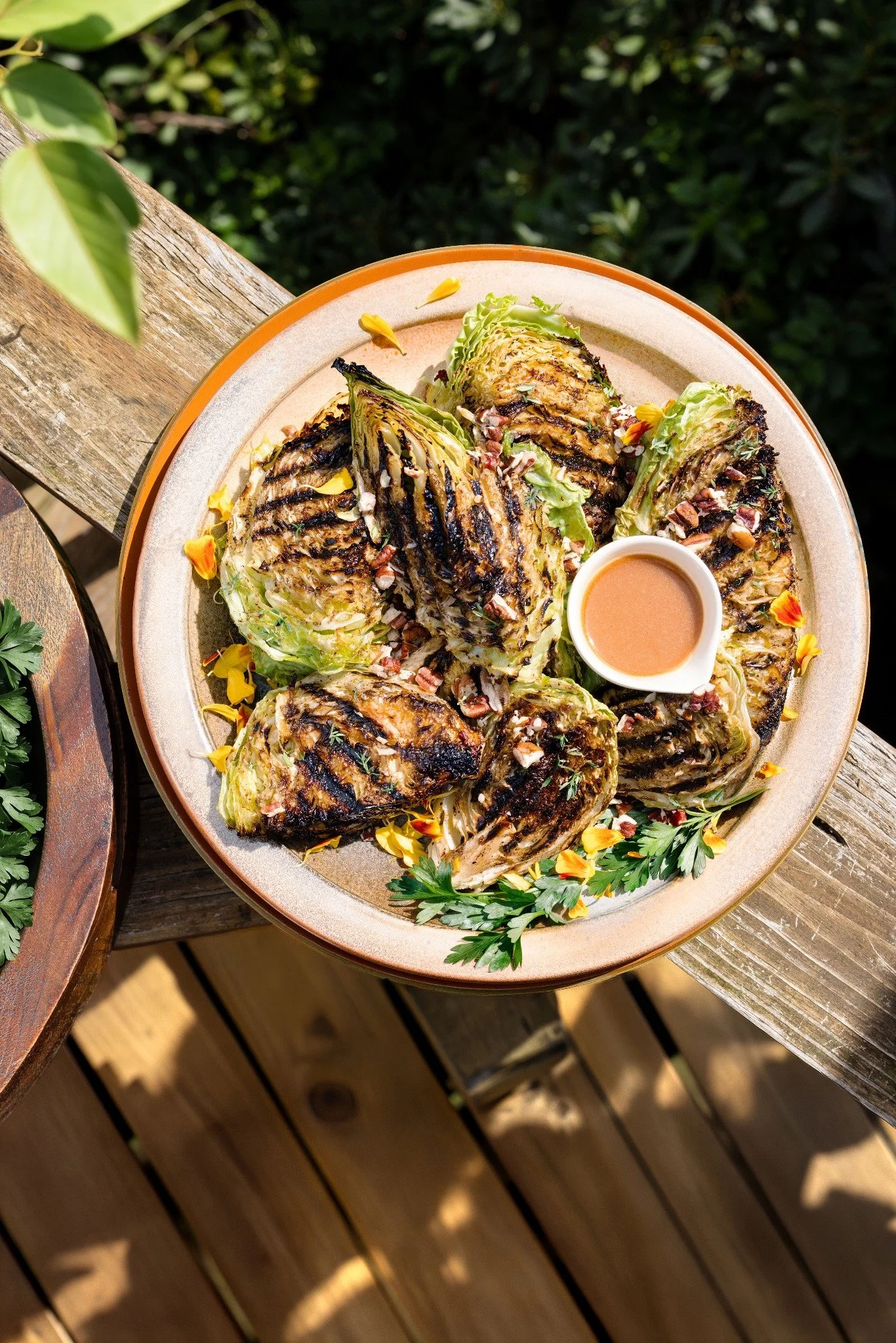 Hospitality — Charred cabbage with herbs, flowers, and dressing photographed outdoors for an Asheville editorial food story.