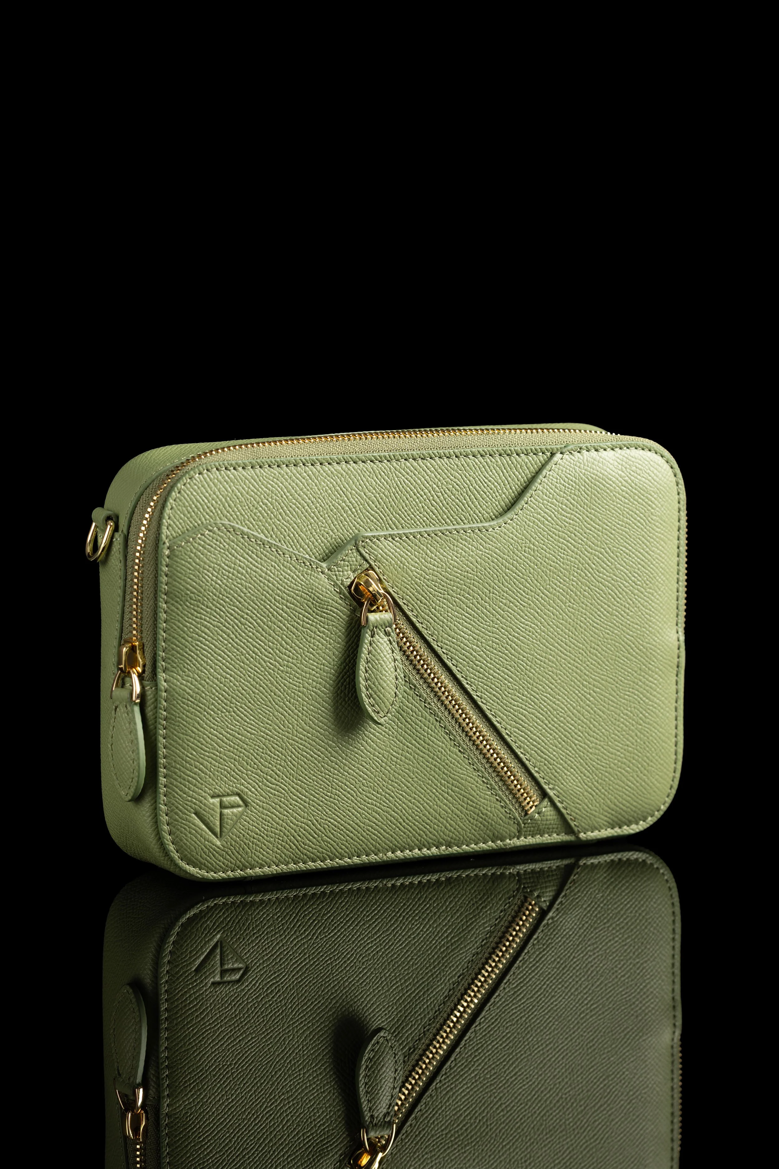 Editorial & Brand — Sage leather travel bag with gold hardware photographed as a refined product still life.