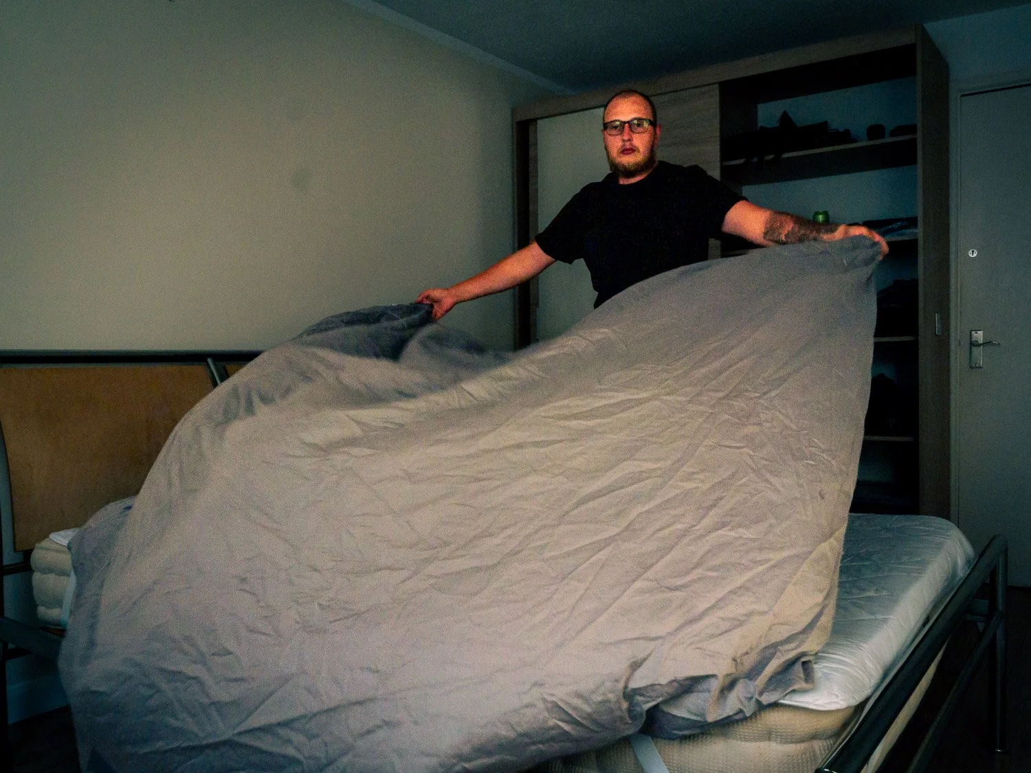 A man making a bed in a bedroom.