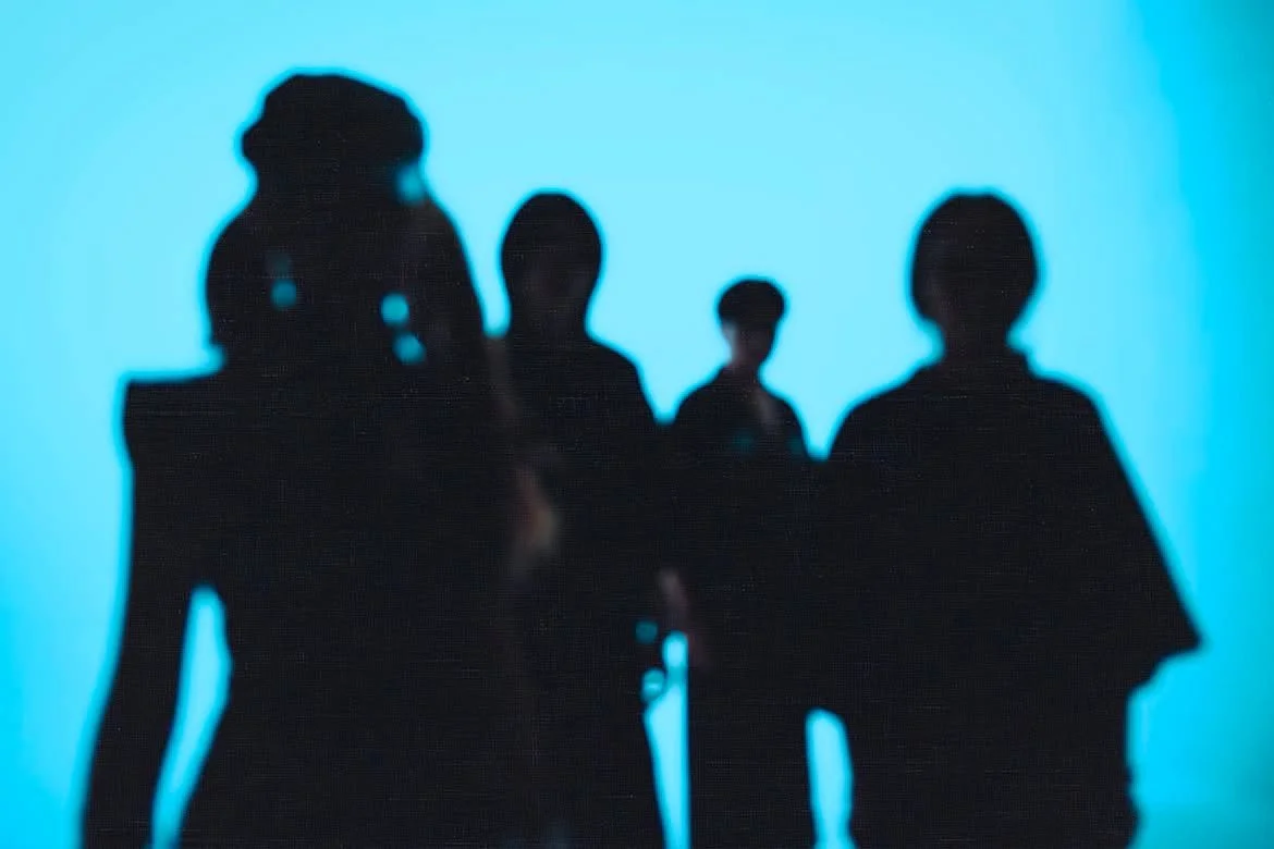Silhouettes of four people, all members of P.H.0, standing against a blue background.