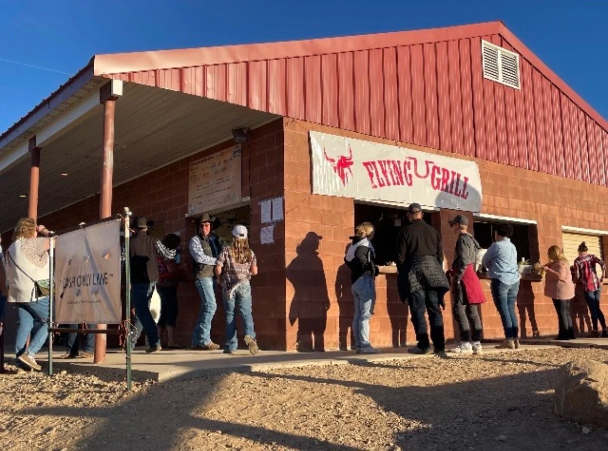 People standing in line outside a barbecue restaurant named "Bingo & Grill" with a line of people waiting to order food.