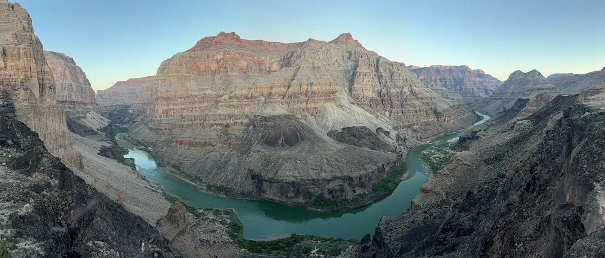 A panoramic view of the Grand Canyon with the Colorado River winding through the deep canyon.