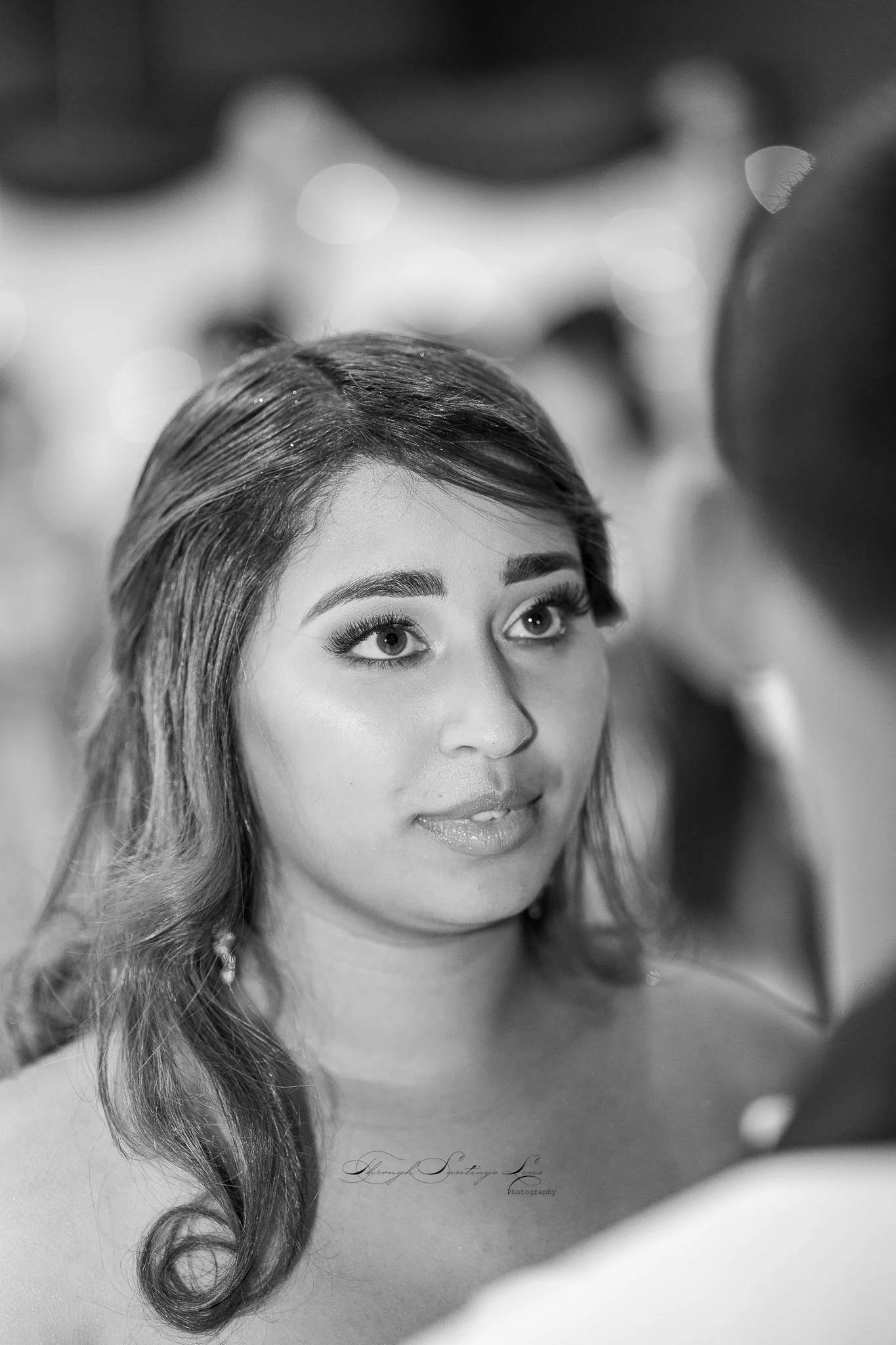 Black and white photo of a young woman with wavy hair and makeup, looking slightly to her left.