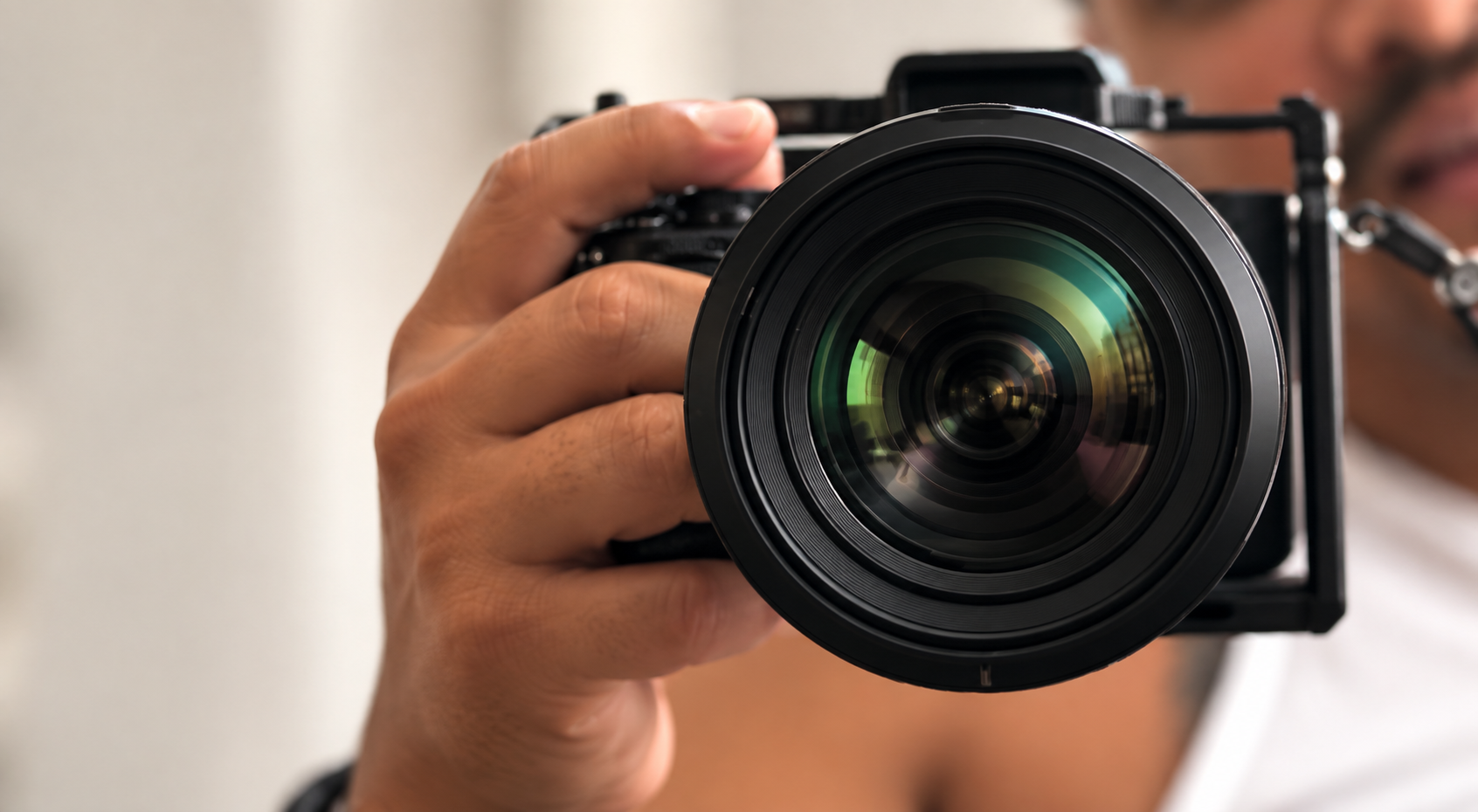 Close-up of a person holding a professional camera with a large lens, aiming it forward.