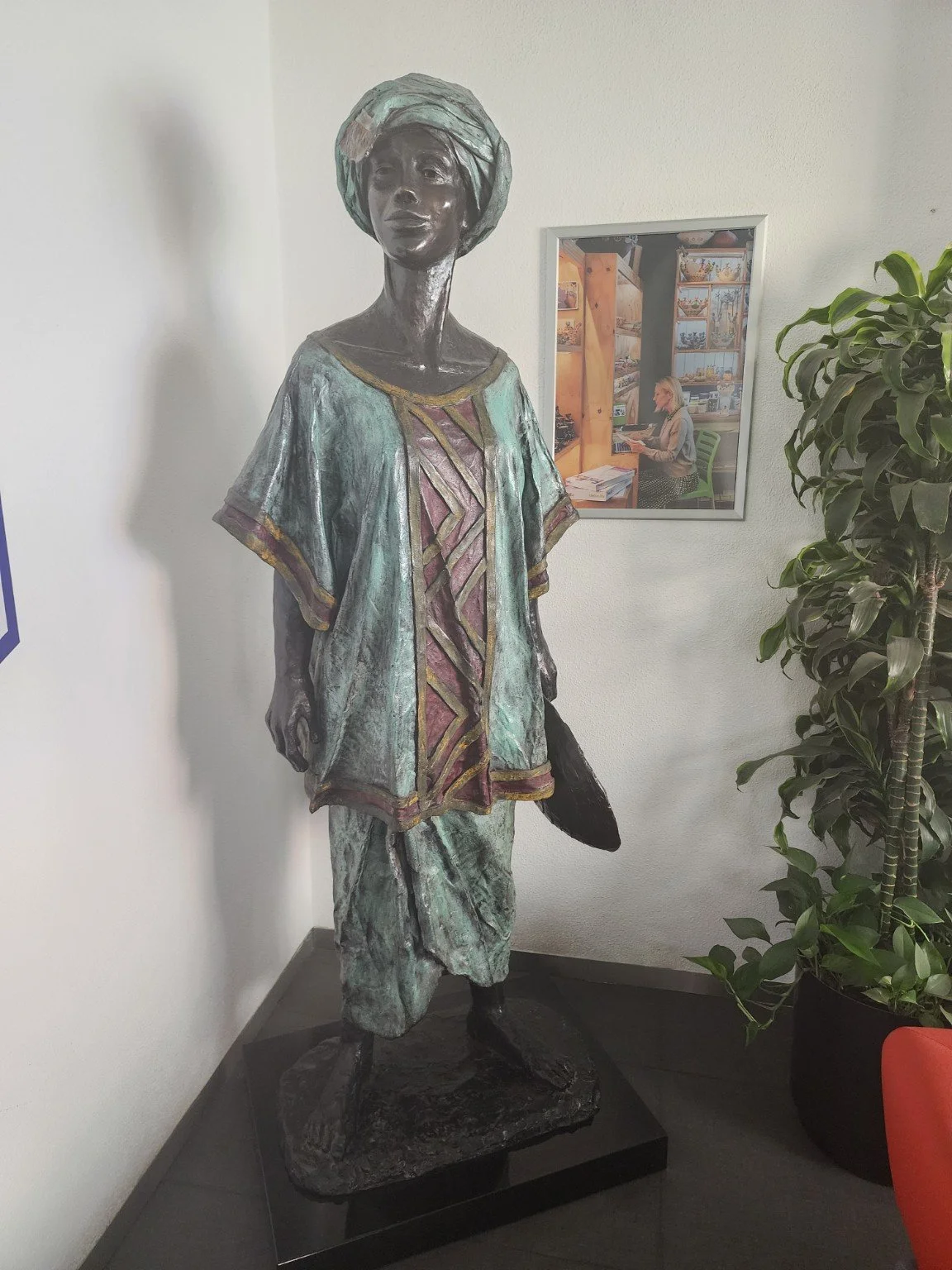 A sculpted figure in a teal garment, photographed by Prachel during a cultural visit.