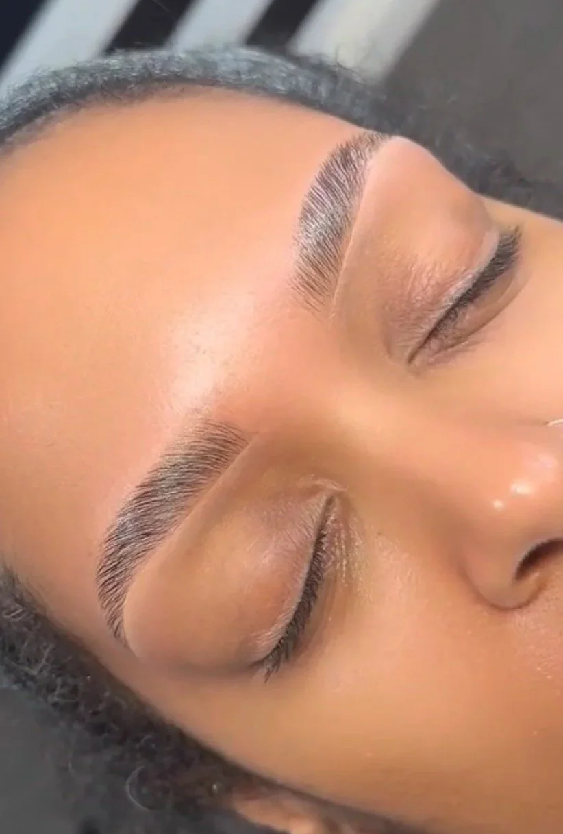Close-up of a person's face with well-groomed eyebrows and smooth skin, eyes closed.