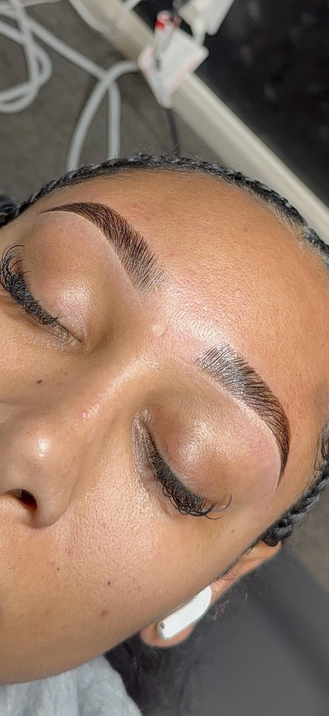 Close-up of a woman's face with freshly groomed eyebrows, closed eyes, and smooth skin.