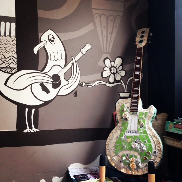 this 2013 sculpture in situ in Googies cafe in 2013, next to a mural by El Davoo. the guitar is covered in broken china