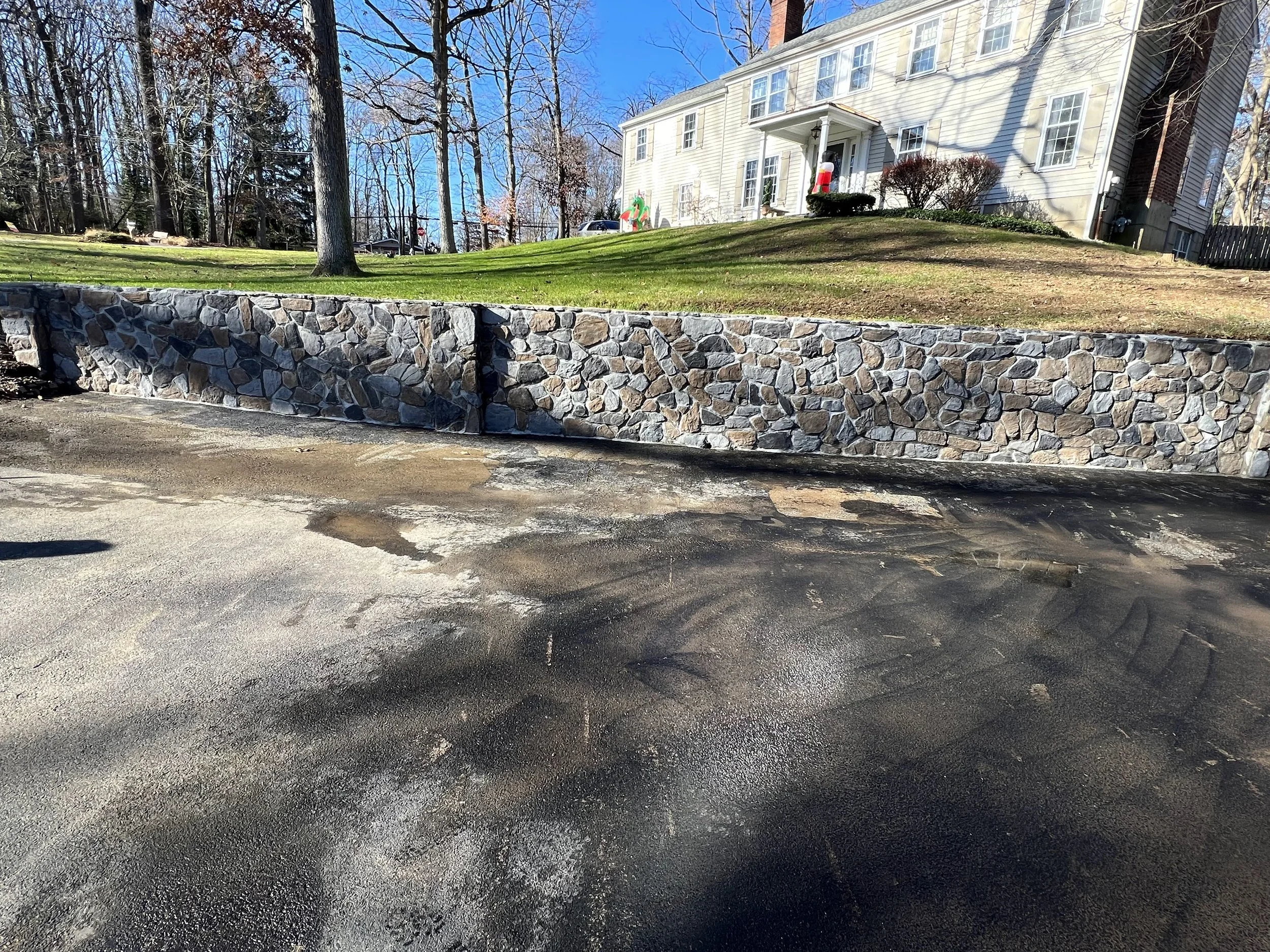 Natural stone retaining wall featuring a terraced landscape design, helping define different ground elevations while adding a rustic appearance to the residential property.