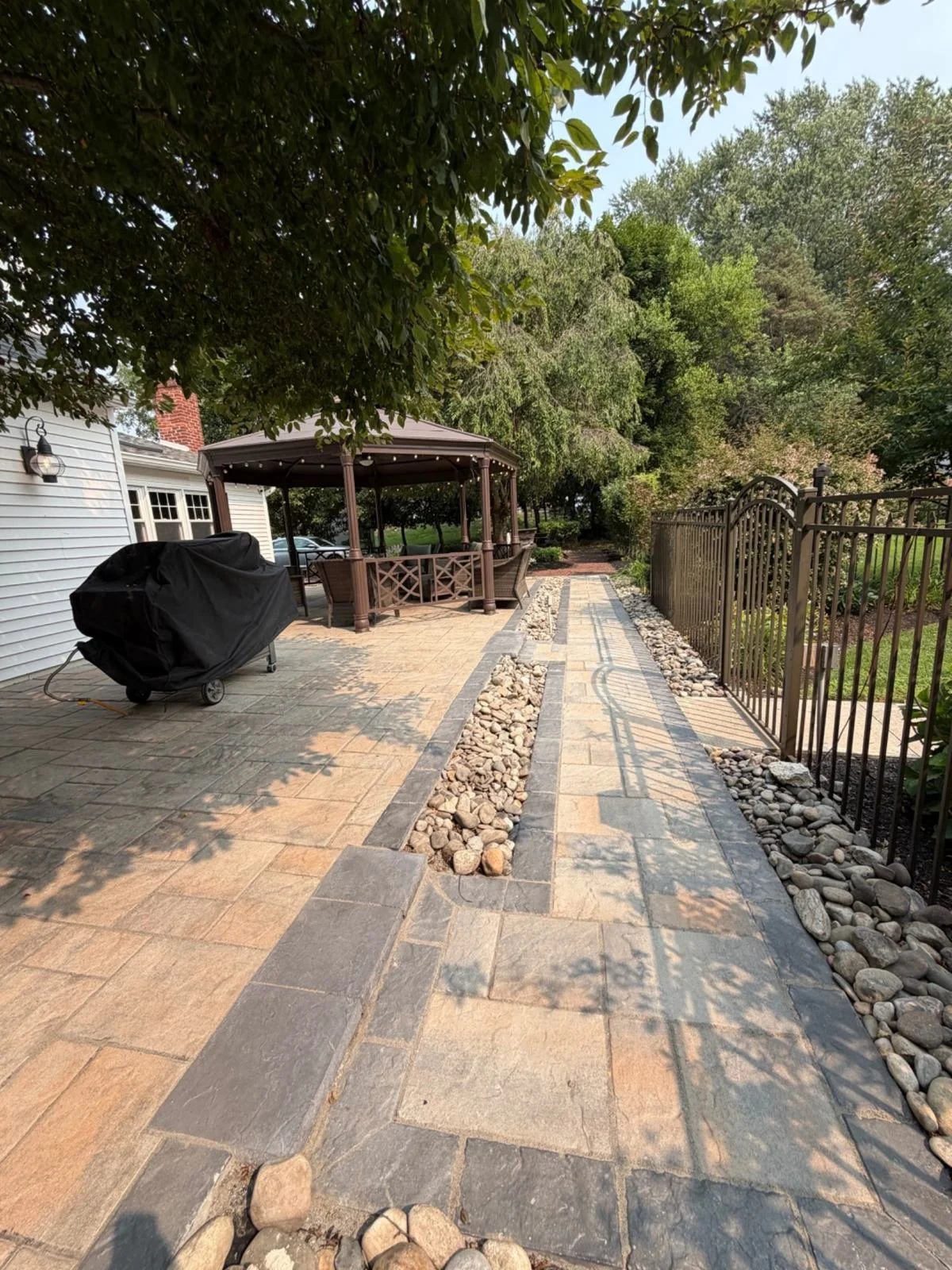 Residential garden pathway featuring natural stone paving, contrasting gravel accents, and stone edging that defines the walking area alongside a landscaped yard.