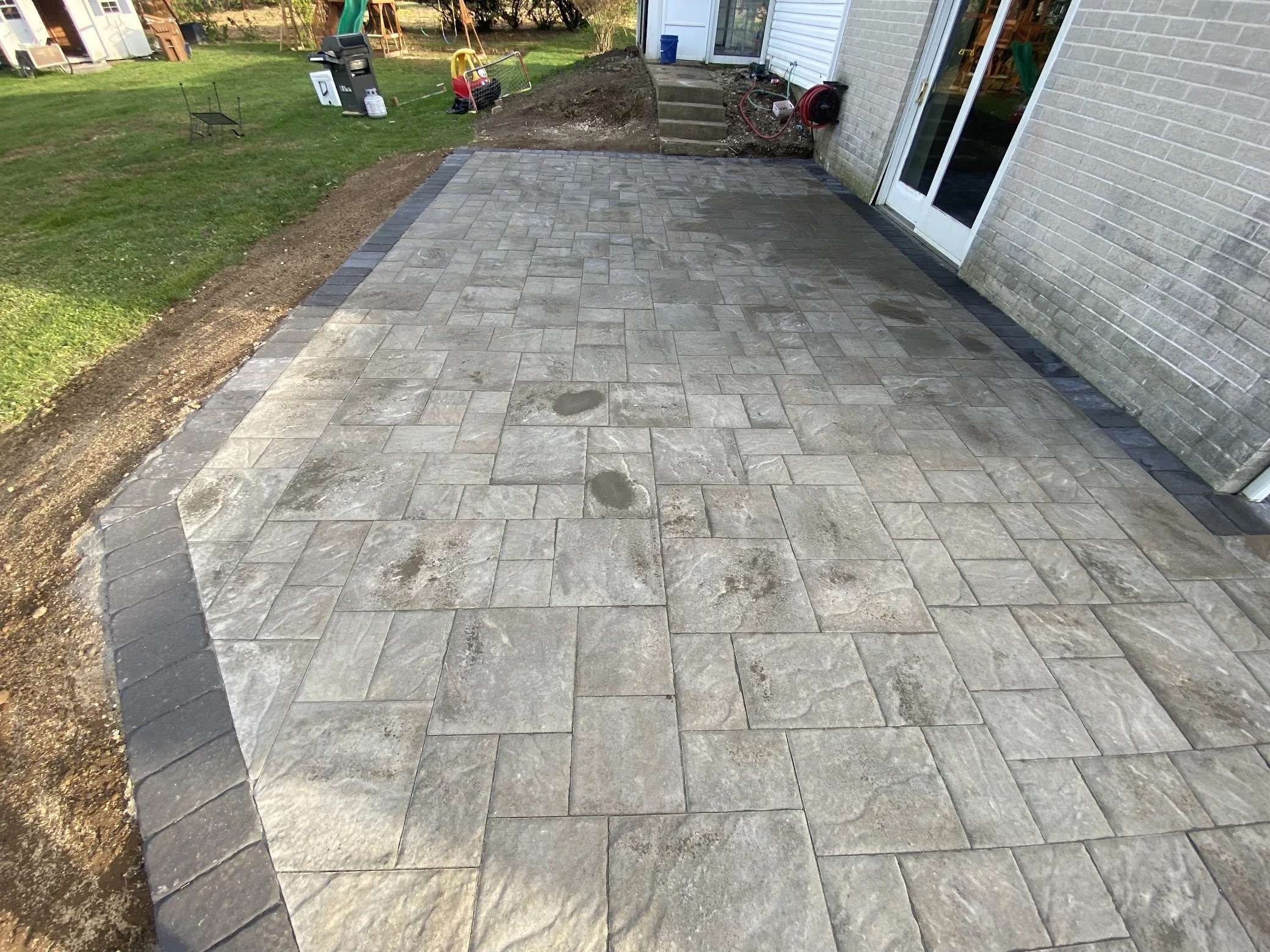 Residential outdoor surface featuring a decorative stone-style pattern and defined edges, providing a practical patio area with a textured finish.