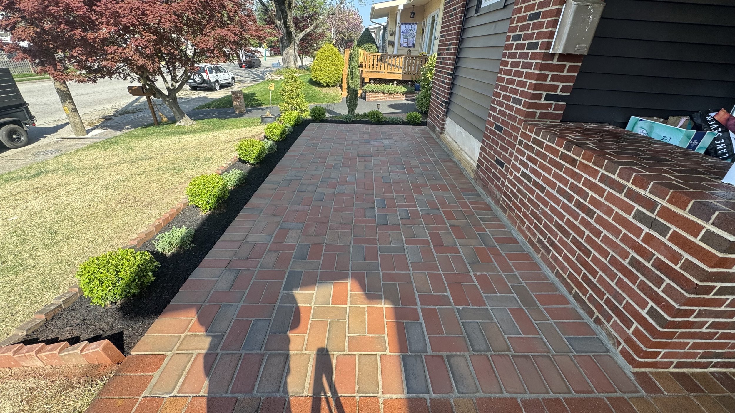 Residential brick paver walkway featuring a geometric pattern, contrasting brick colors, and straight edging along the side of a home, creating a distinctive outdoor pathway.