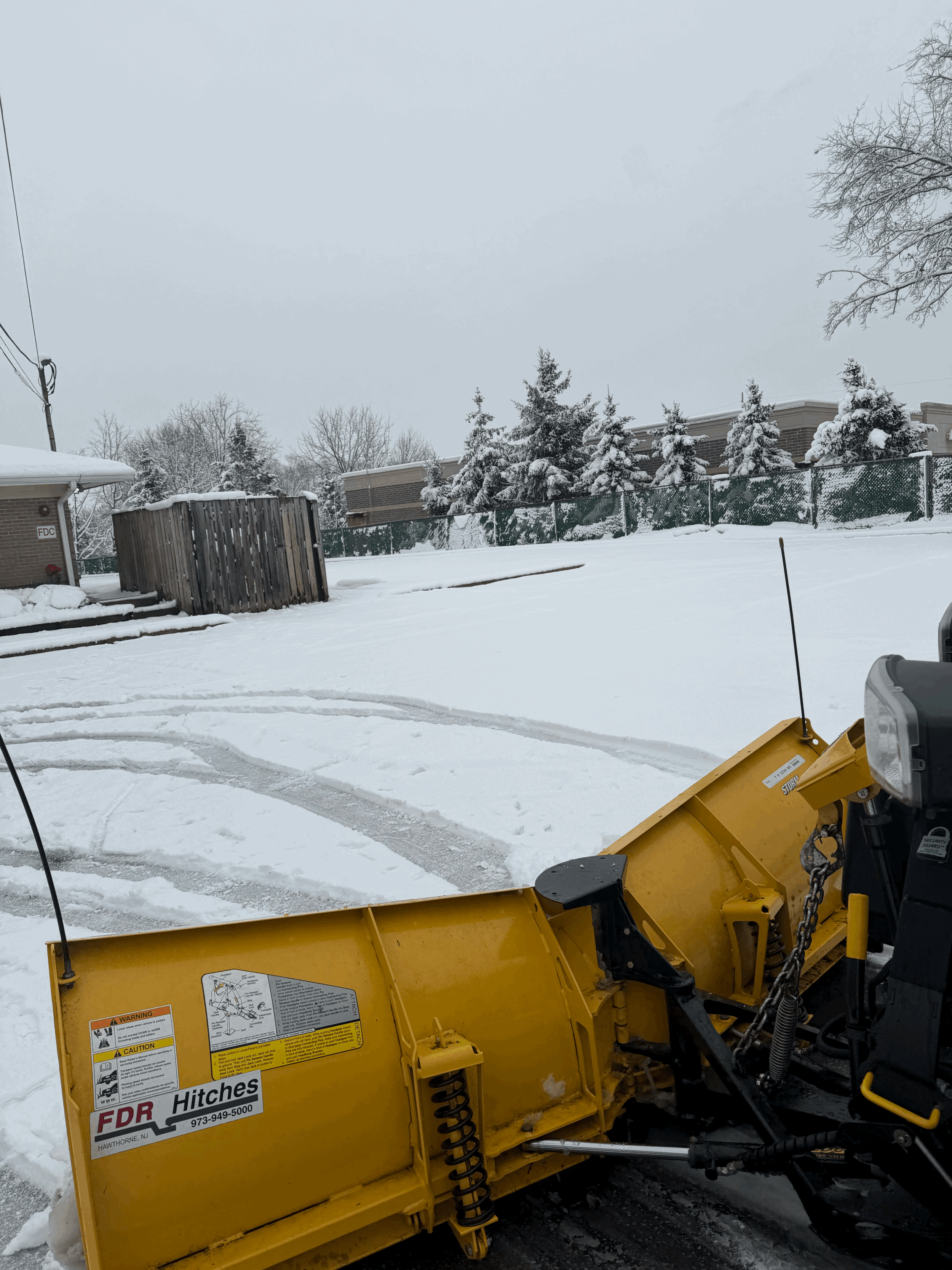 Heavy-duty snow removal equipment with a front-mounted plow clearing accumulated snow from a large outdoor area, helping maintain accessible surfaces during winter conditions.