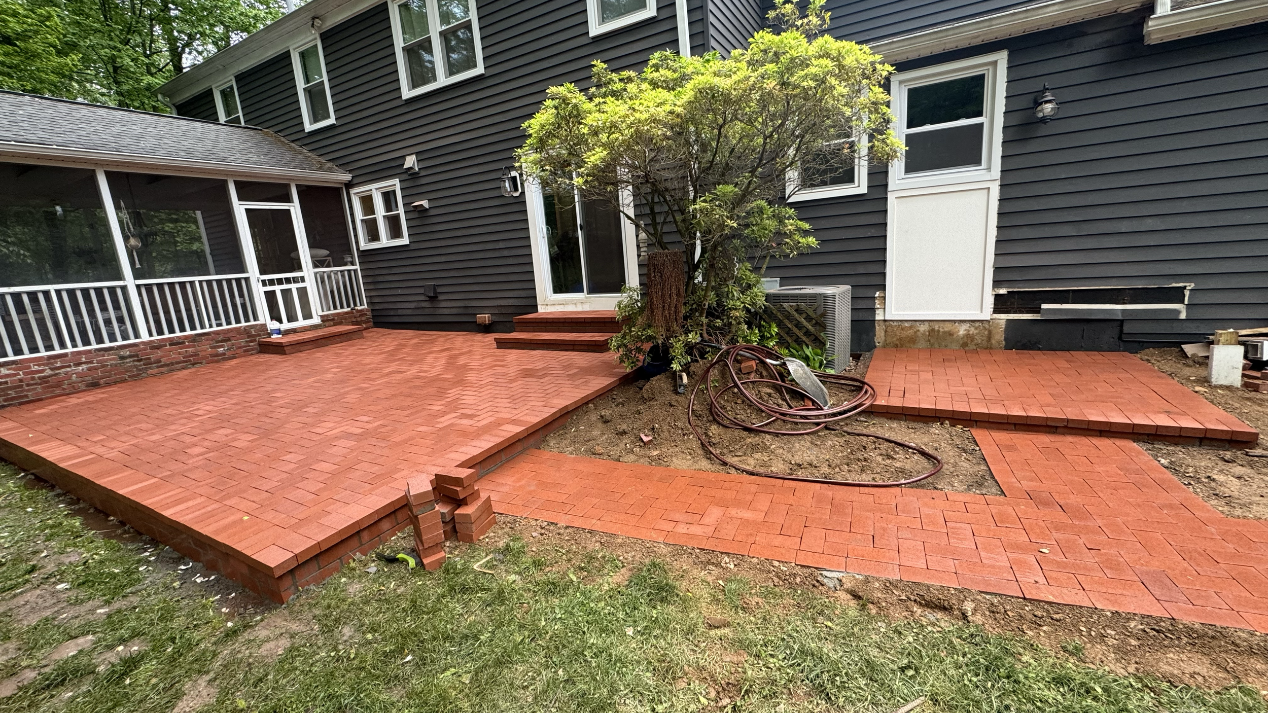 Residential brick paver walkway featuring a geometric pattern, contrasting brick colors, and straight edging along the side of a home, creating a distinctive outdoor pathway.