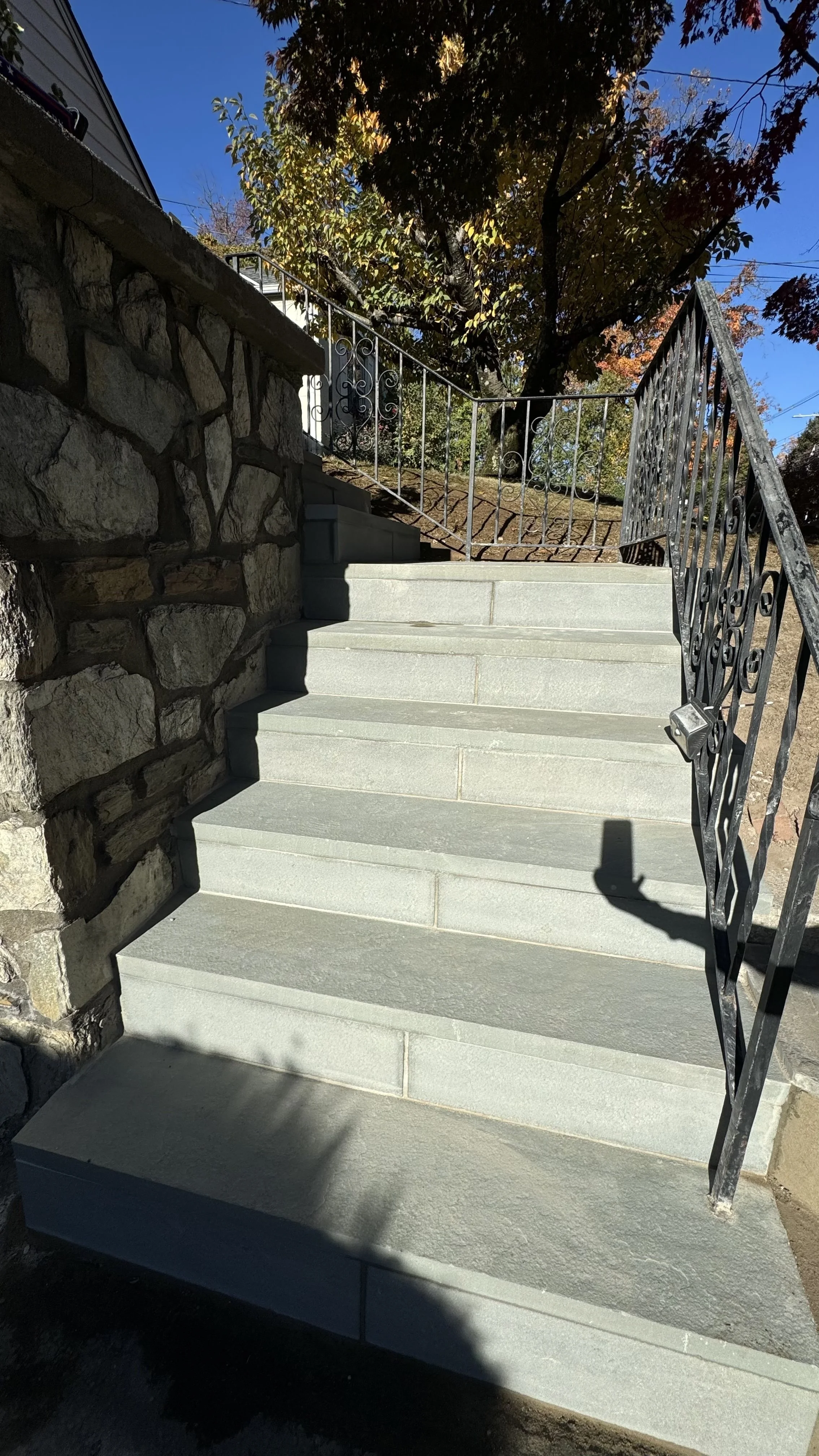 Outdoor flagstone stairway bordered by natural stone retaining walls, creating a durable pedestrian entrance with a clean, structured appearance.