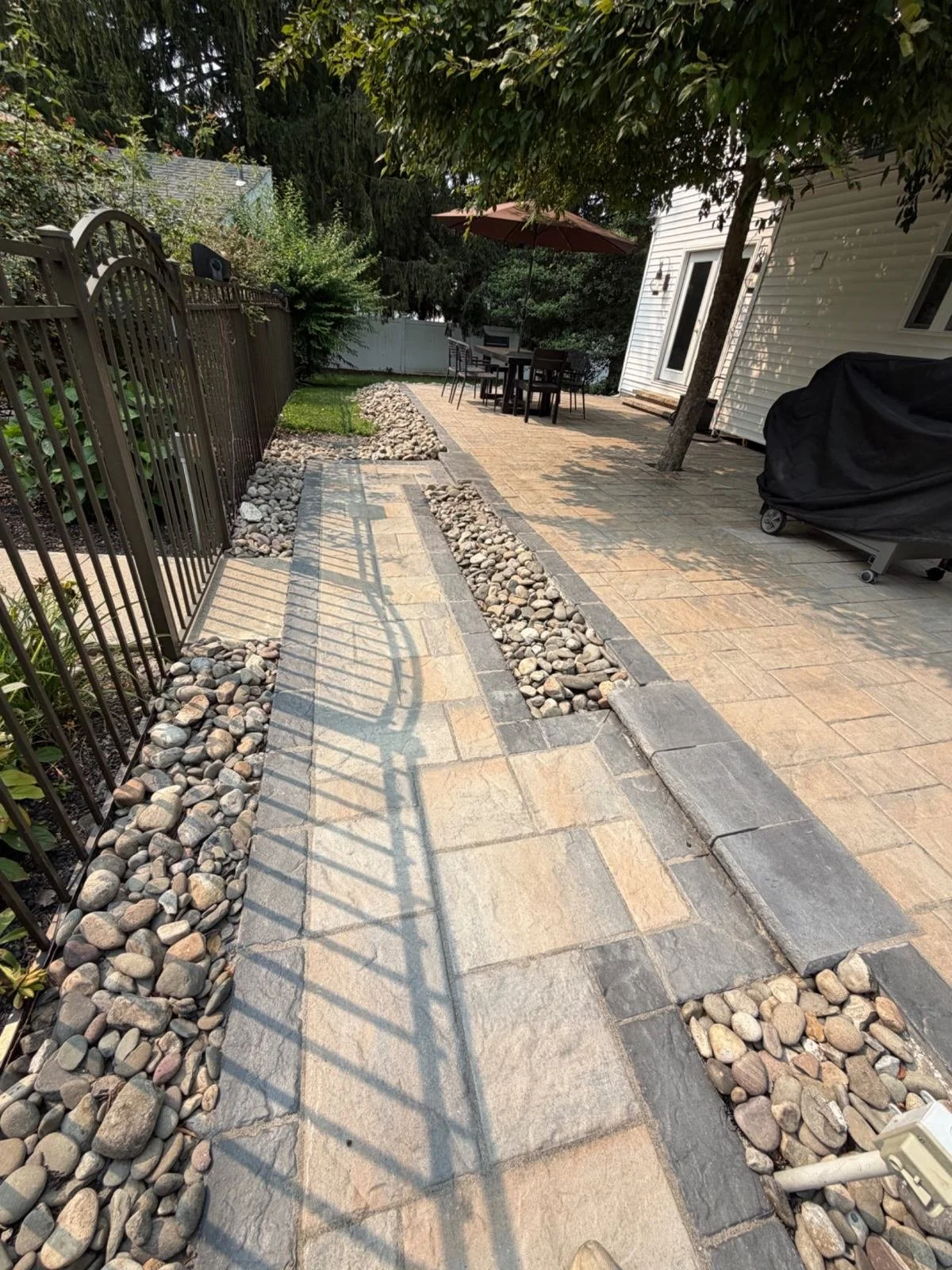 Residential garden pathway featuring natural stone paving, contrasting gravel accents, and stone edging that defines the walking area alongside a landscaped yard.